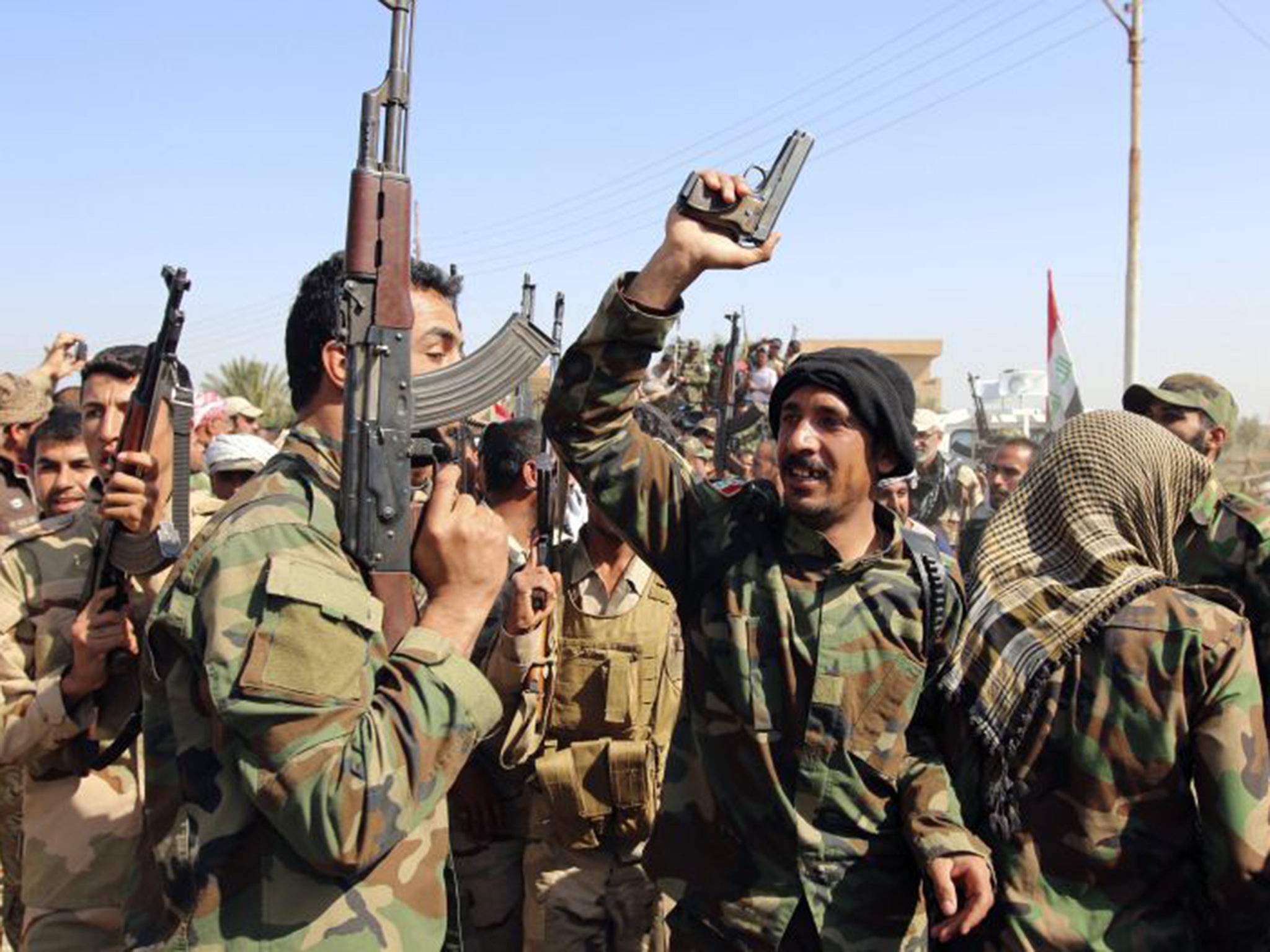 Iraqi security forces and Shia fighters chant slogans as they gather at Udhaim dam, north of Baghdad, where they have been massing in preparation for an attack on Isis along the Tigris River