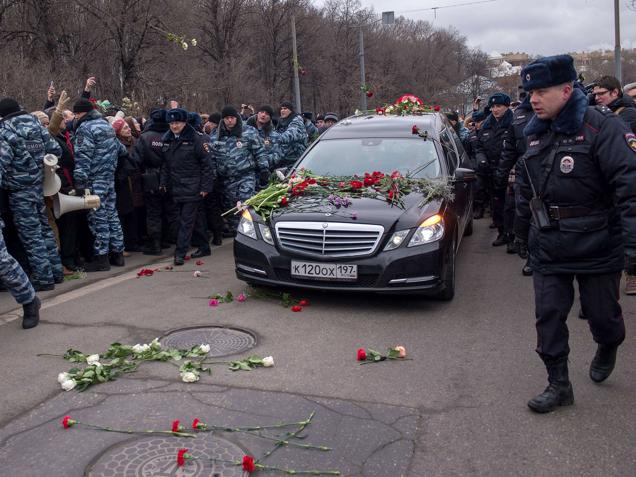 People throw flowers on a road in Moscow, as a car transports the coffin of Boris Nemtsov to the cemetery