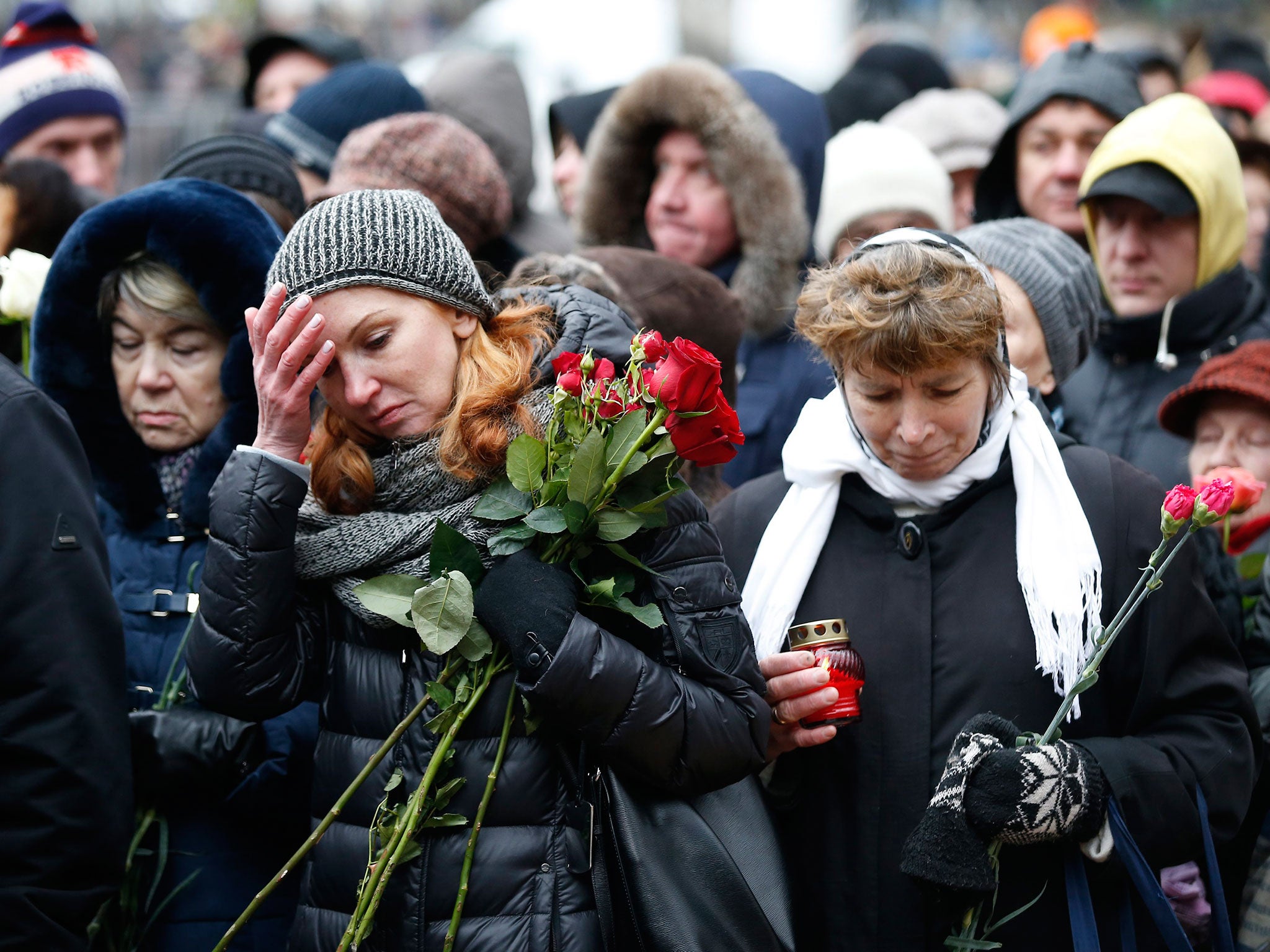 Women react while waiting to pay their last respects