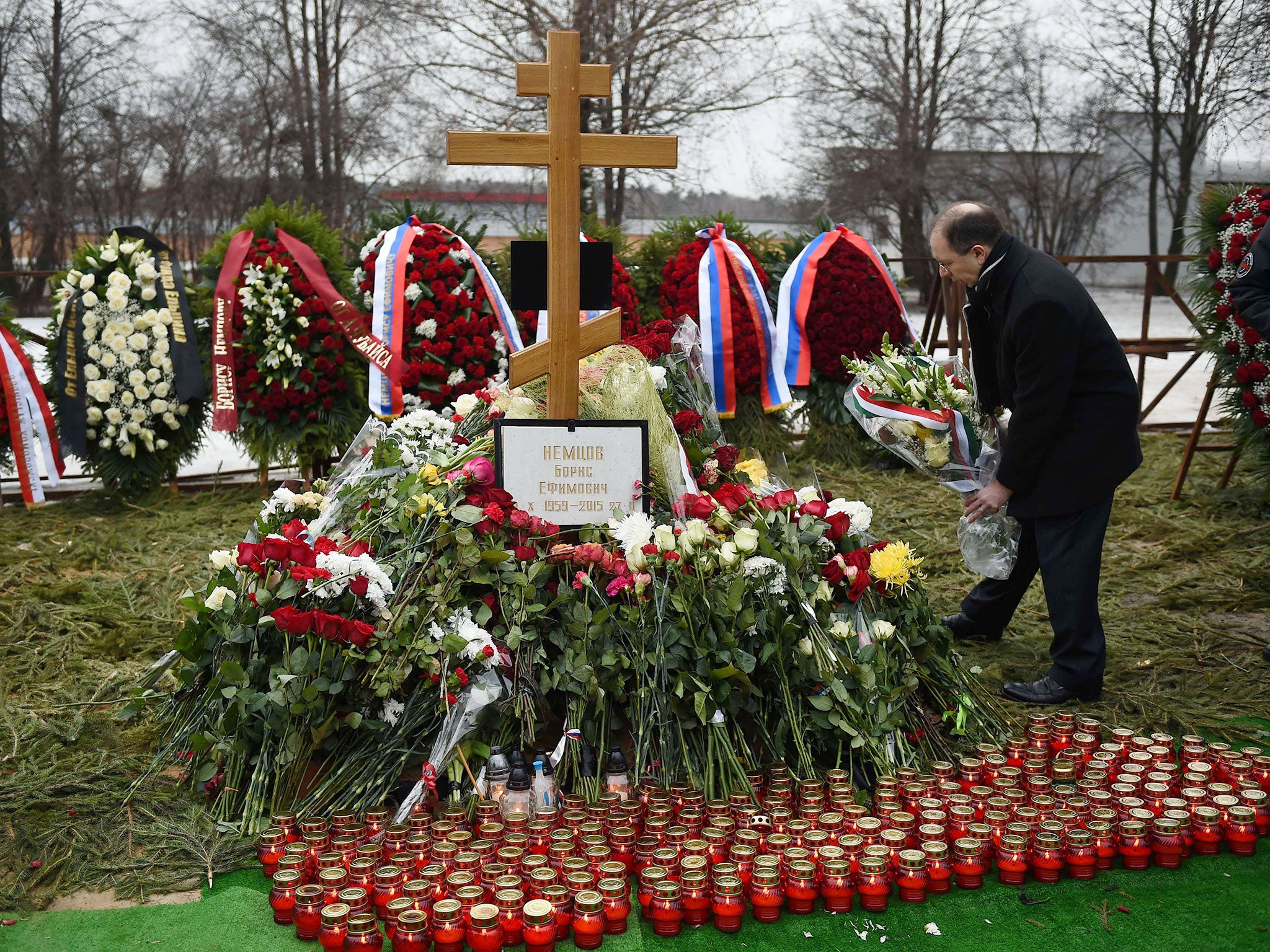 A man lays flowers at the grave