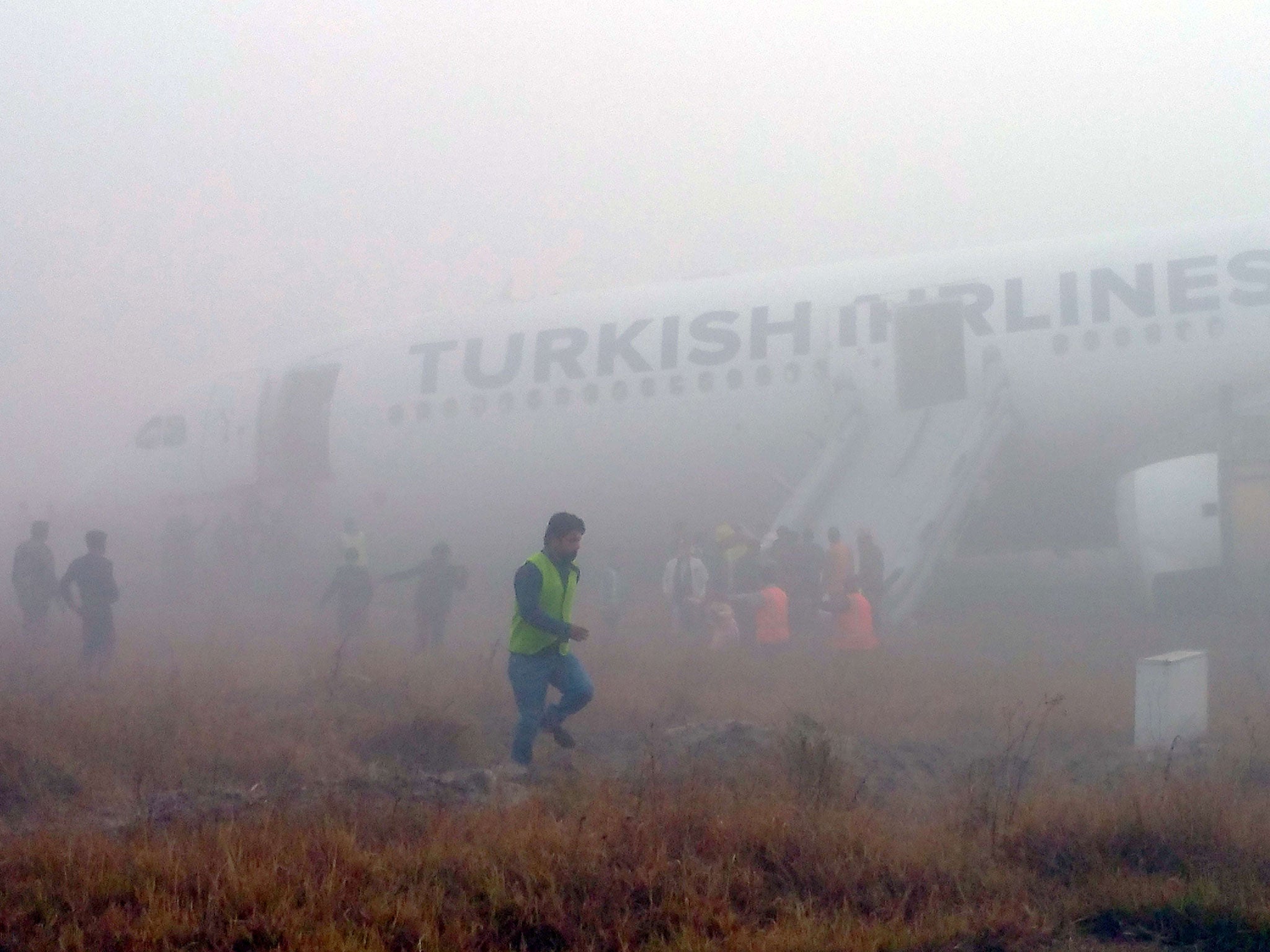 Passengers leave a Turkish Airlines plane which skidded off the runway on landing