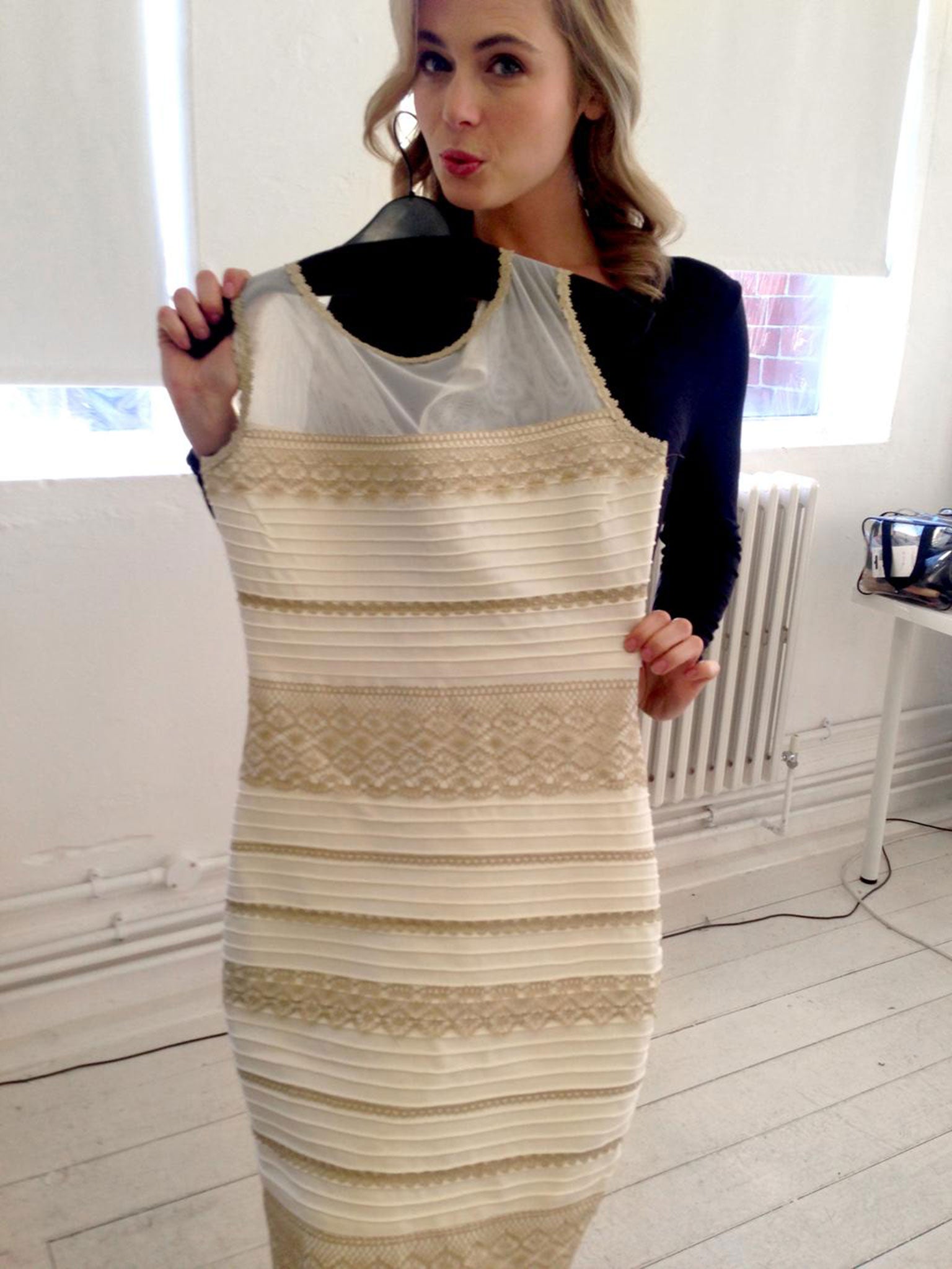 Model poses holding the white and gold dress