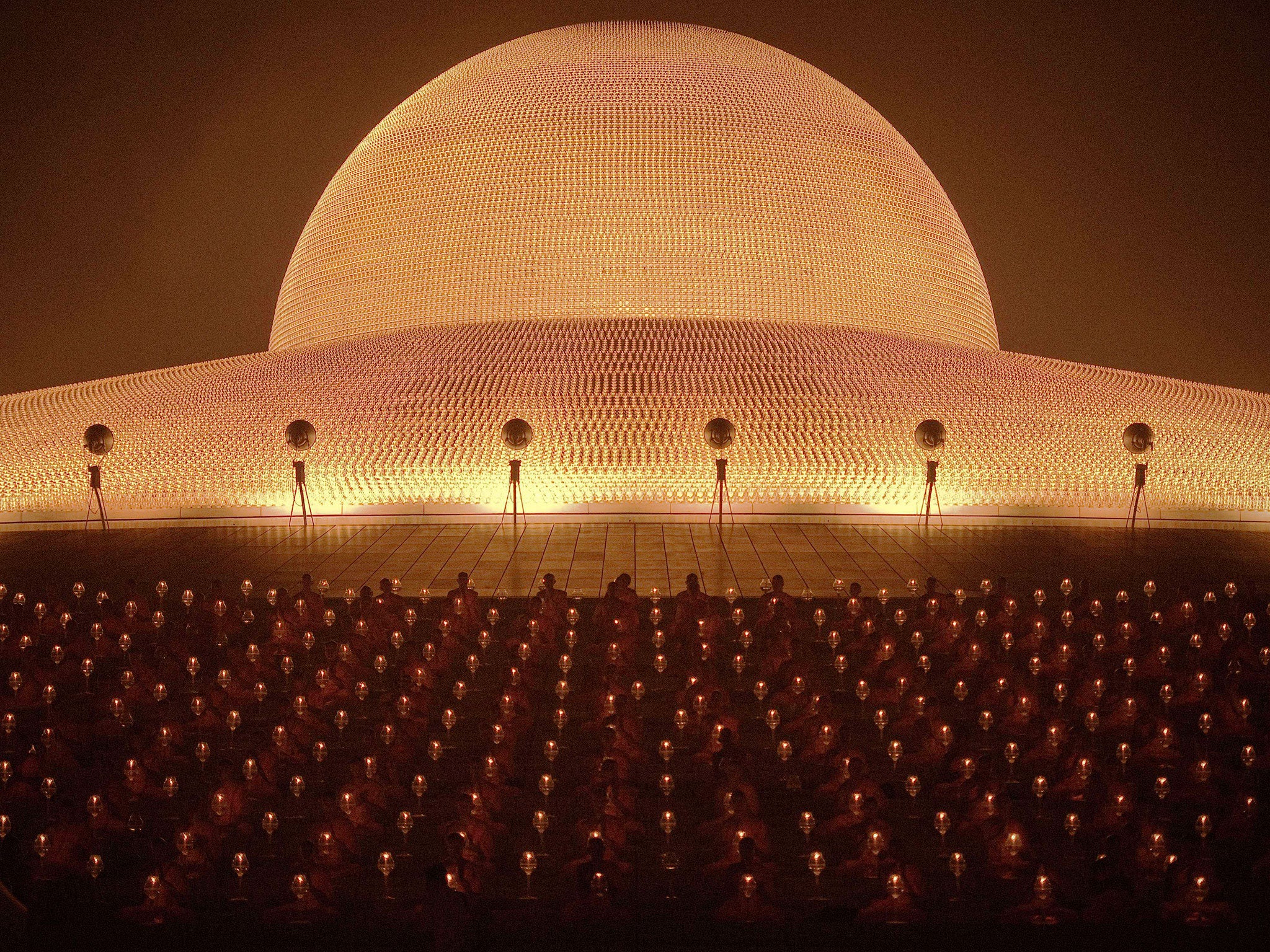 Buddhist monks light candles and pray during a ceremony at the Dhammakaya Temple in Bangkok, Thailand