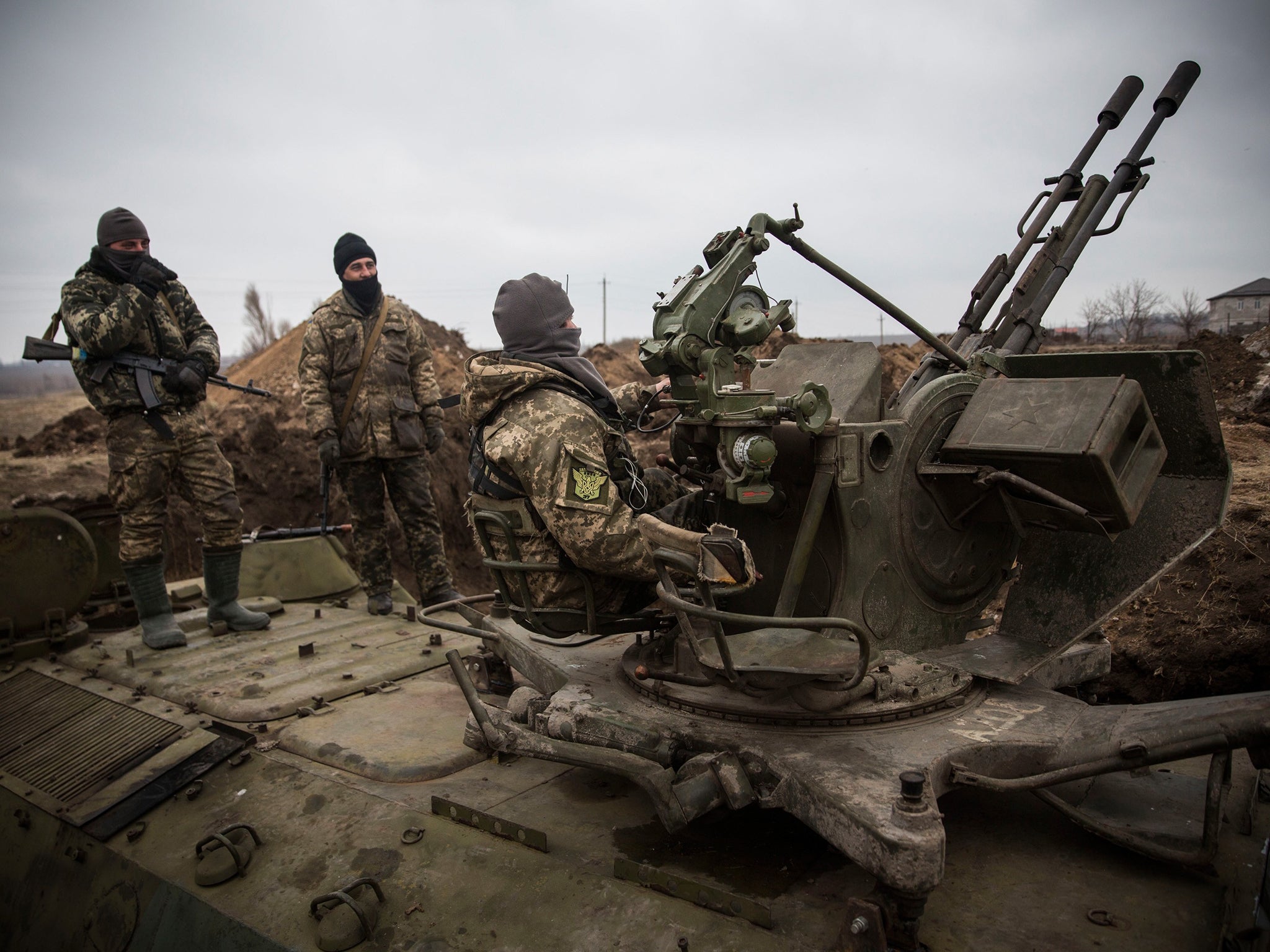 Ukrainian soldiers stand on top of an armored personal carrier