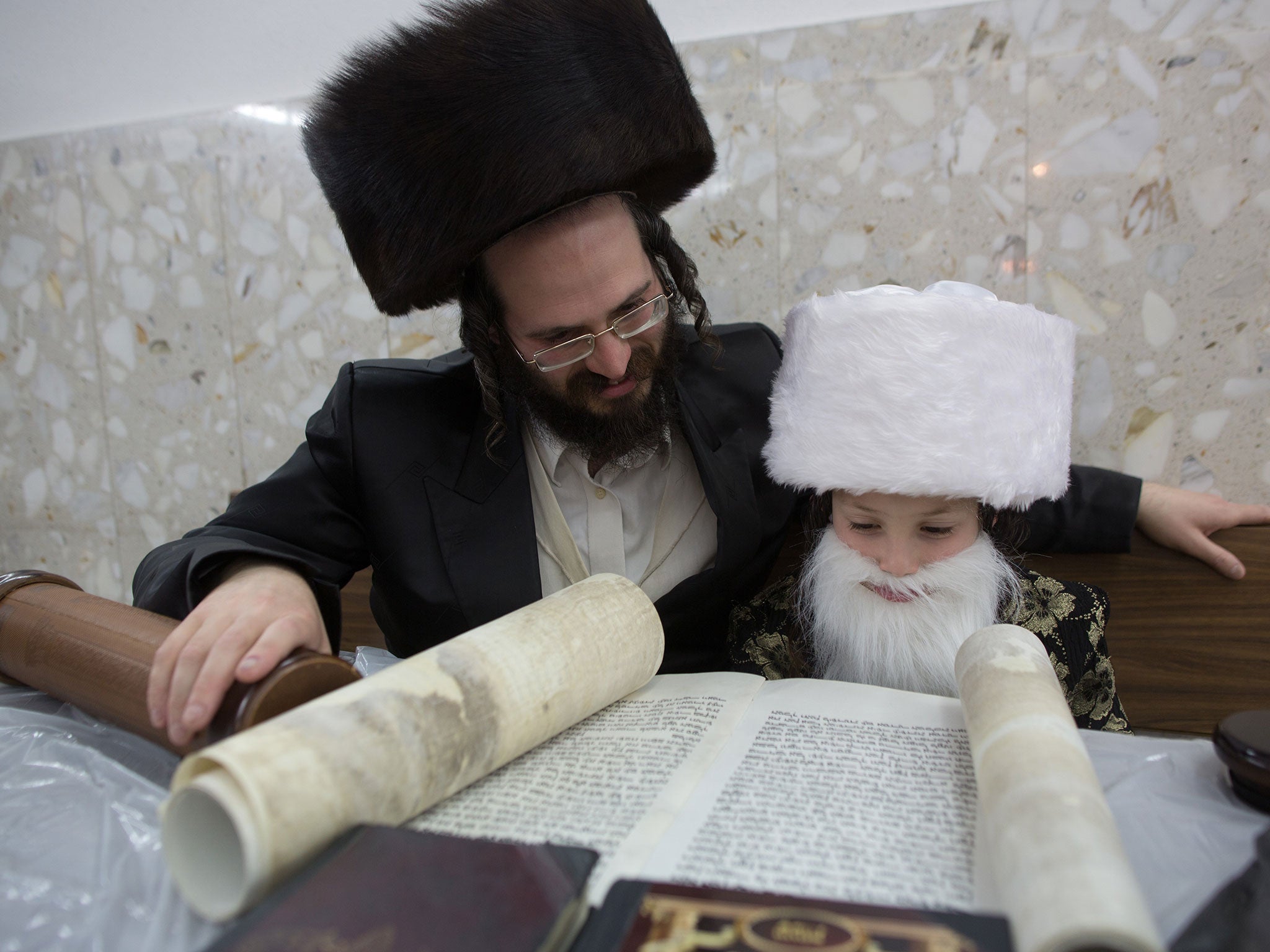 An Ultra-Orthodox Jewish man and his dressed-up child read the book of Esther at a synagogue in the Israeli city of Bnei Brak near the costal city of Tel Aviv on March 4, 2015 during the feast of Purim.