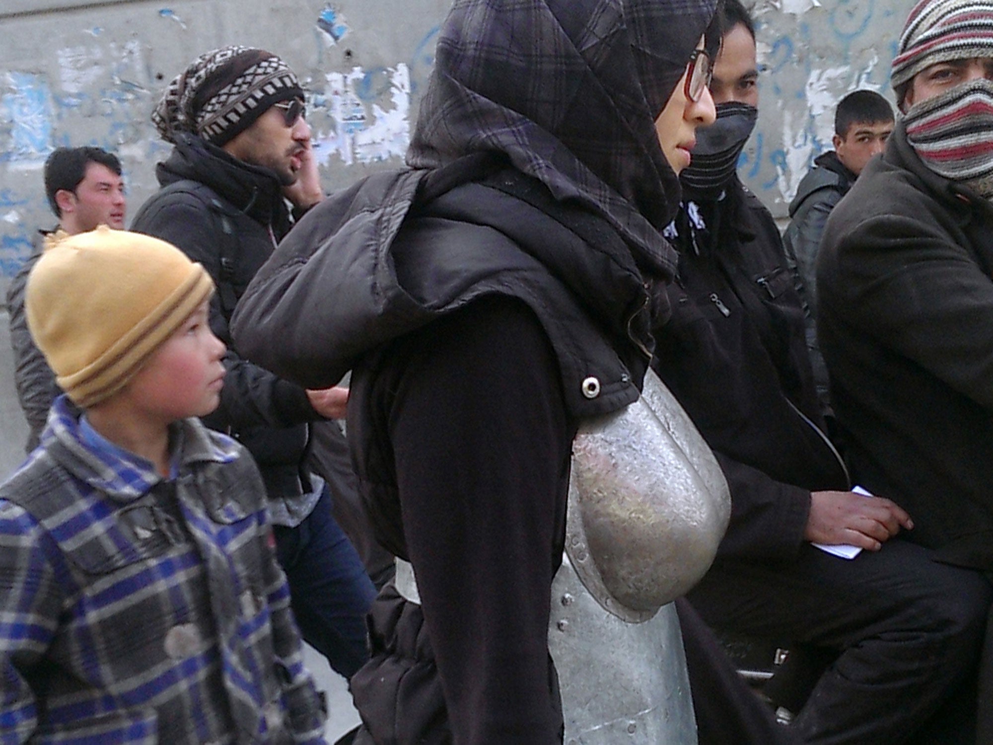 Afghan performance artist Kubra Khademi, center, walks with her art piece, a suit of armor with large breasts and buttocks, in a street in Kabul, Afghanistan.