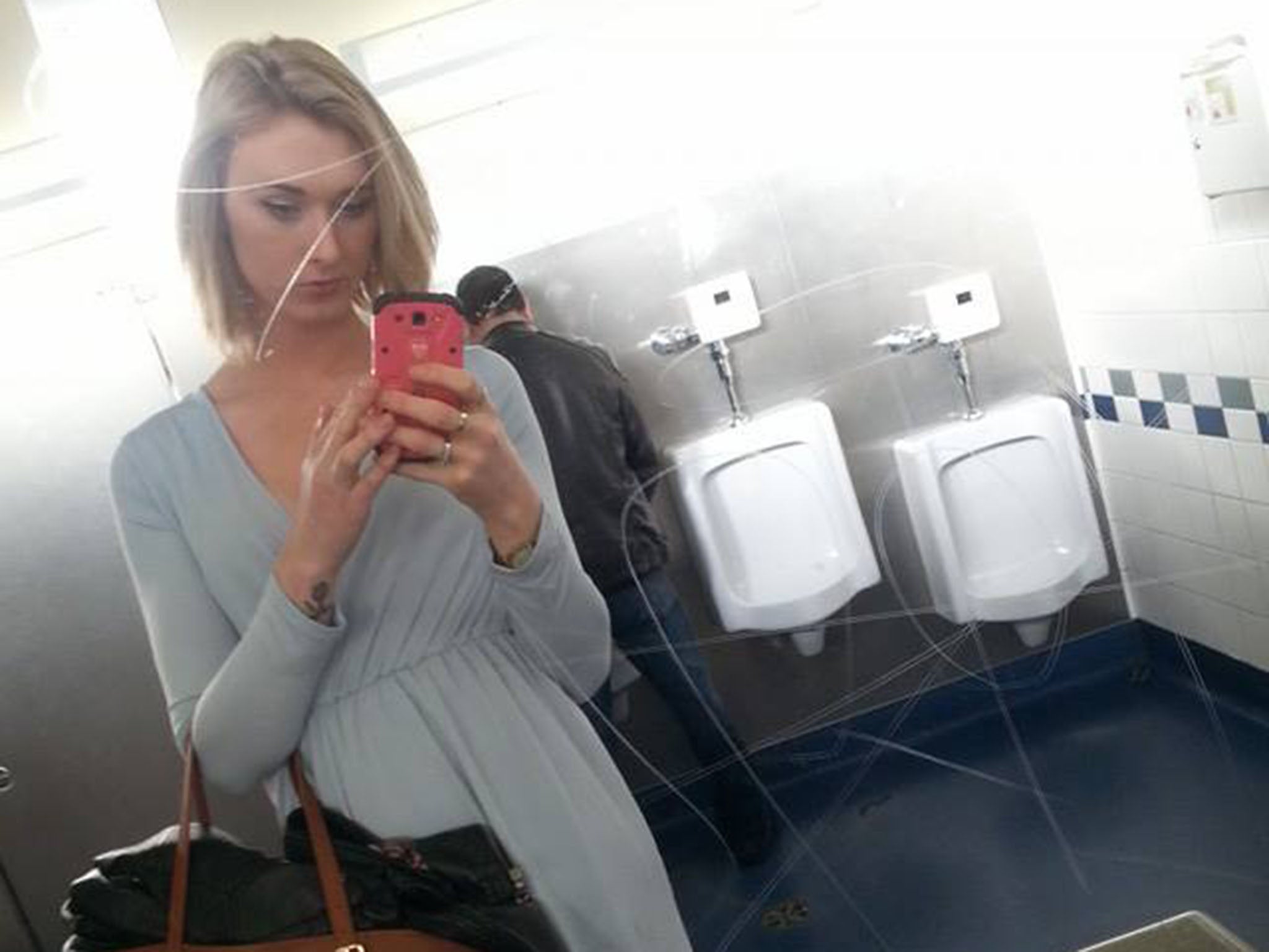 Transgender Brae Carnes poses in front of the men's urinals