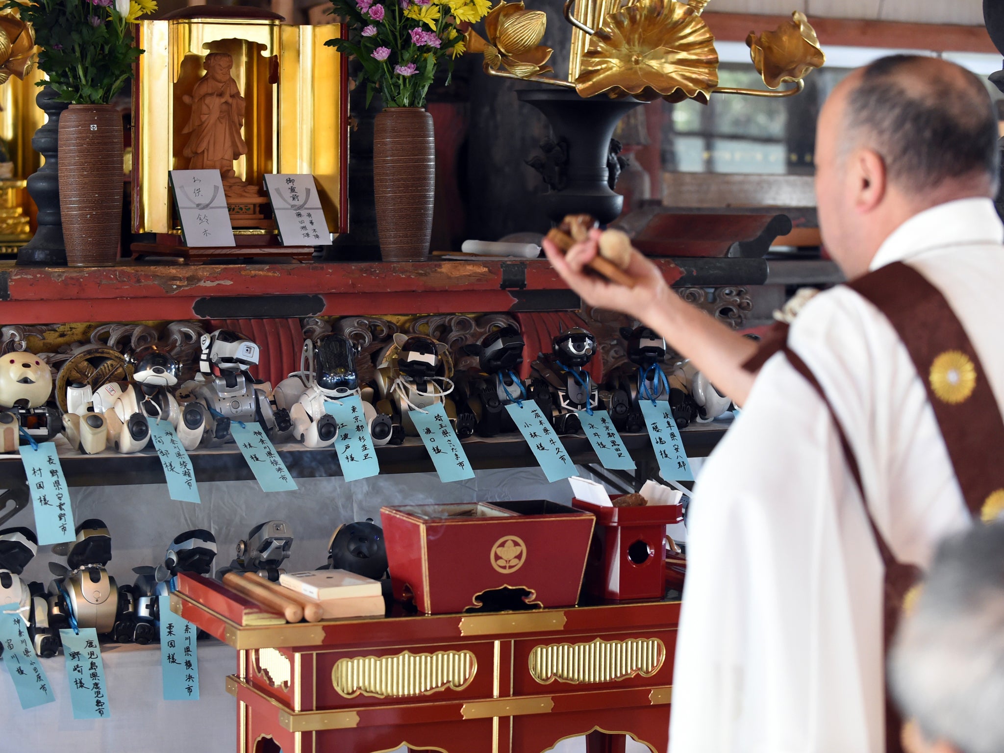 Kofuku-ji temple chief priest Bungen Oi (R) offers a prayer during the funeral for 19 Sony's pet robot AIBOs