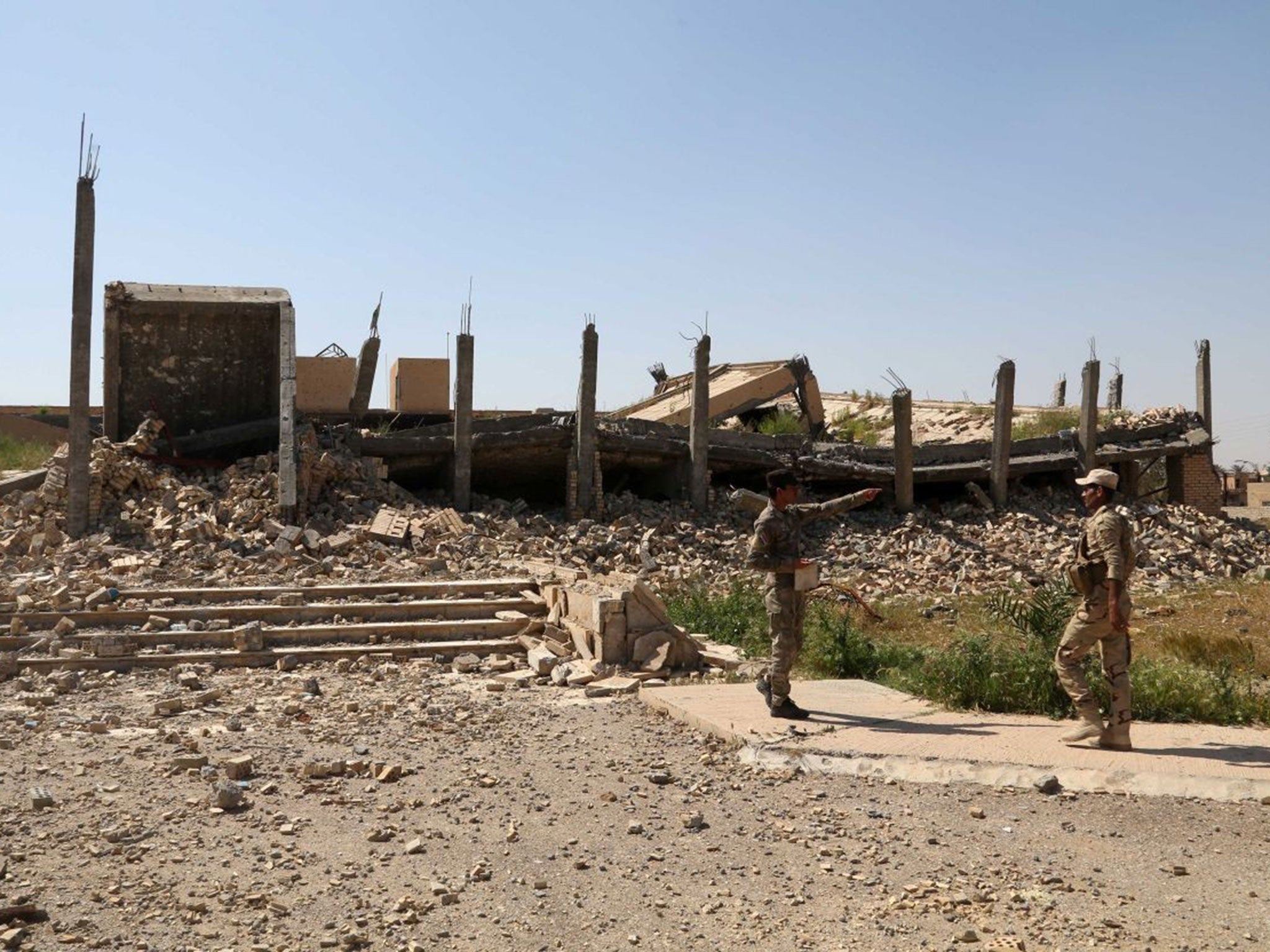 Iraqi soldiers stand next to the demolished tomb of former Iraqi president, Saddam Hussein, in Tikrit, 130km (80 miles) north of Baghdad, Iraq