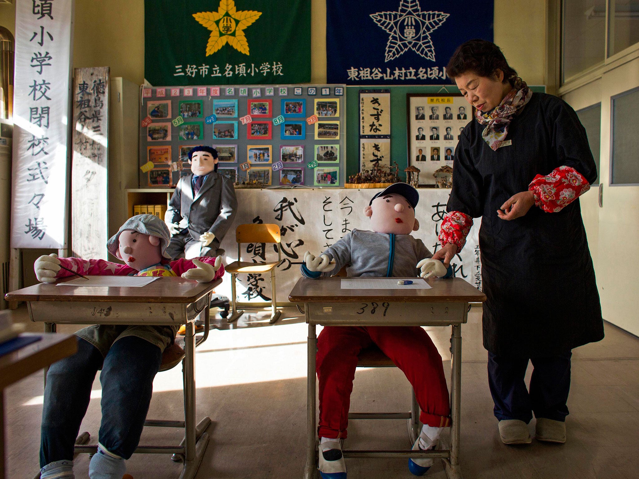 Tsukimi Ayano stands in a classroom with scarecrows at a closed down school in the village of Nagoro