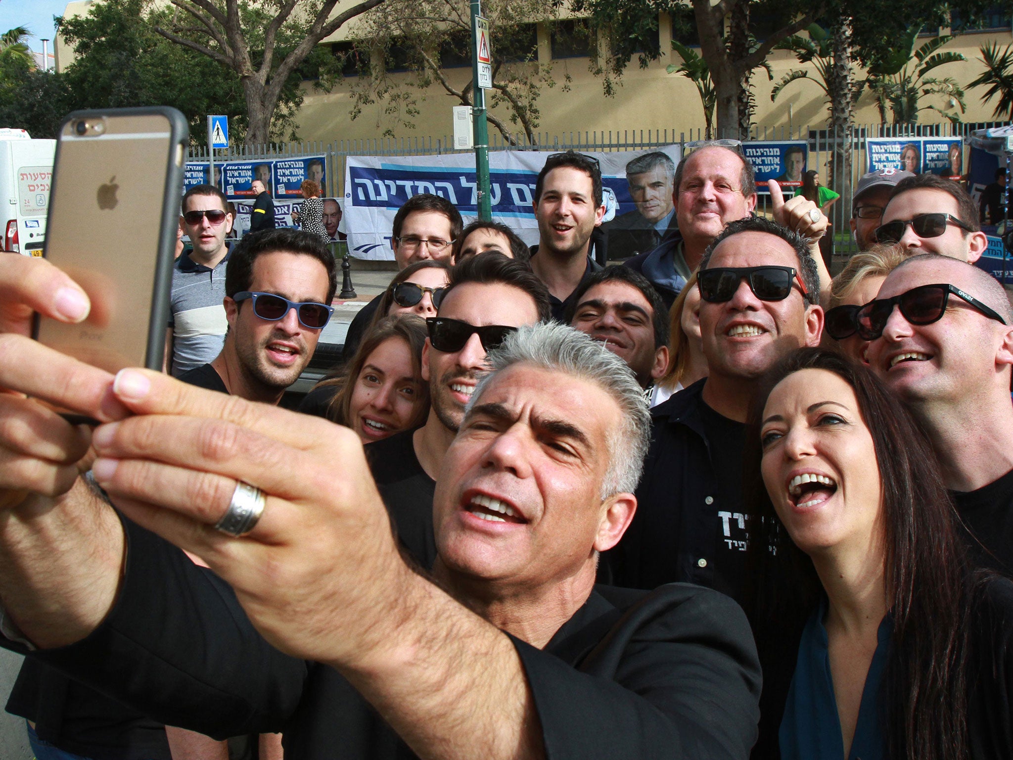 Israeli MP and chairperson of center-right Yesh Atid party, Yair Lapid, takes a selfie with his wife Lihi (R) and his supporters, outside a polling station in Tel Aviv