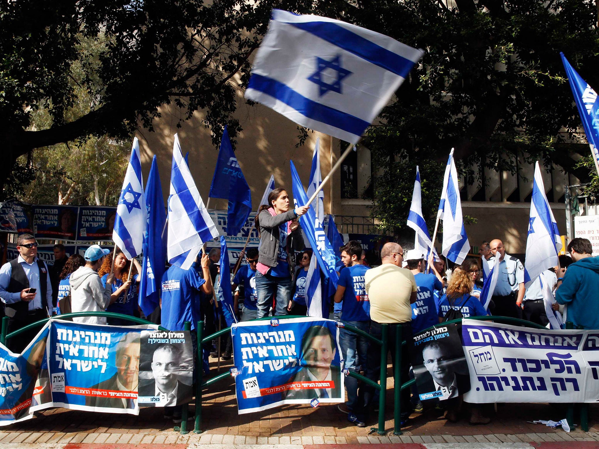 A woman waves an Israeli national flag outside a polling station in Tel Aviv
