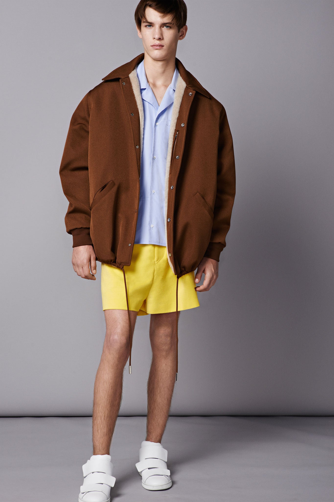 Imperfection is perfect: Eensy-weensy shorts barely peek out below an oversized shirt and bomber jacket, above bare legs and feet shoved into thick, Velcro-tabbed trainers