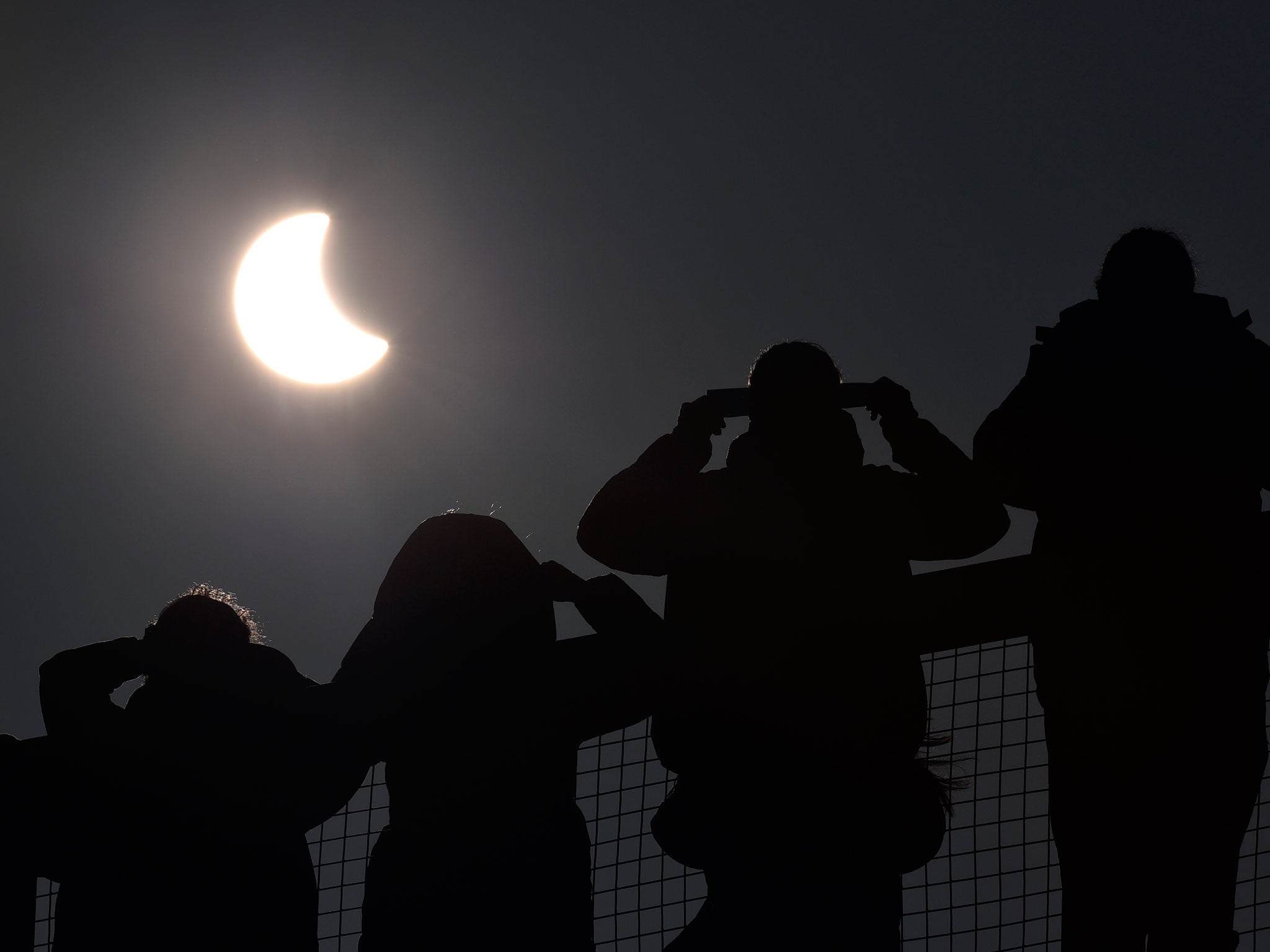 People watch as a solar eclipse begins over the Eden Project near St Austell in Cornwall