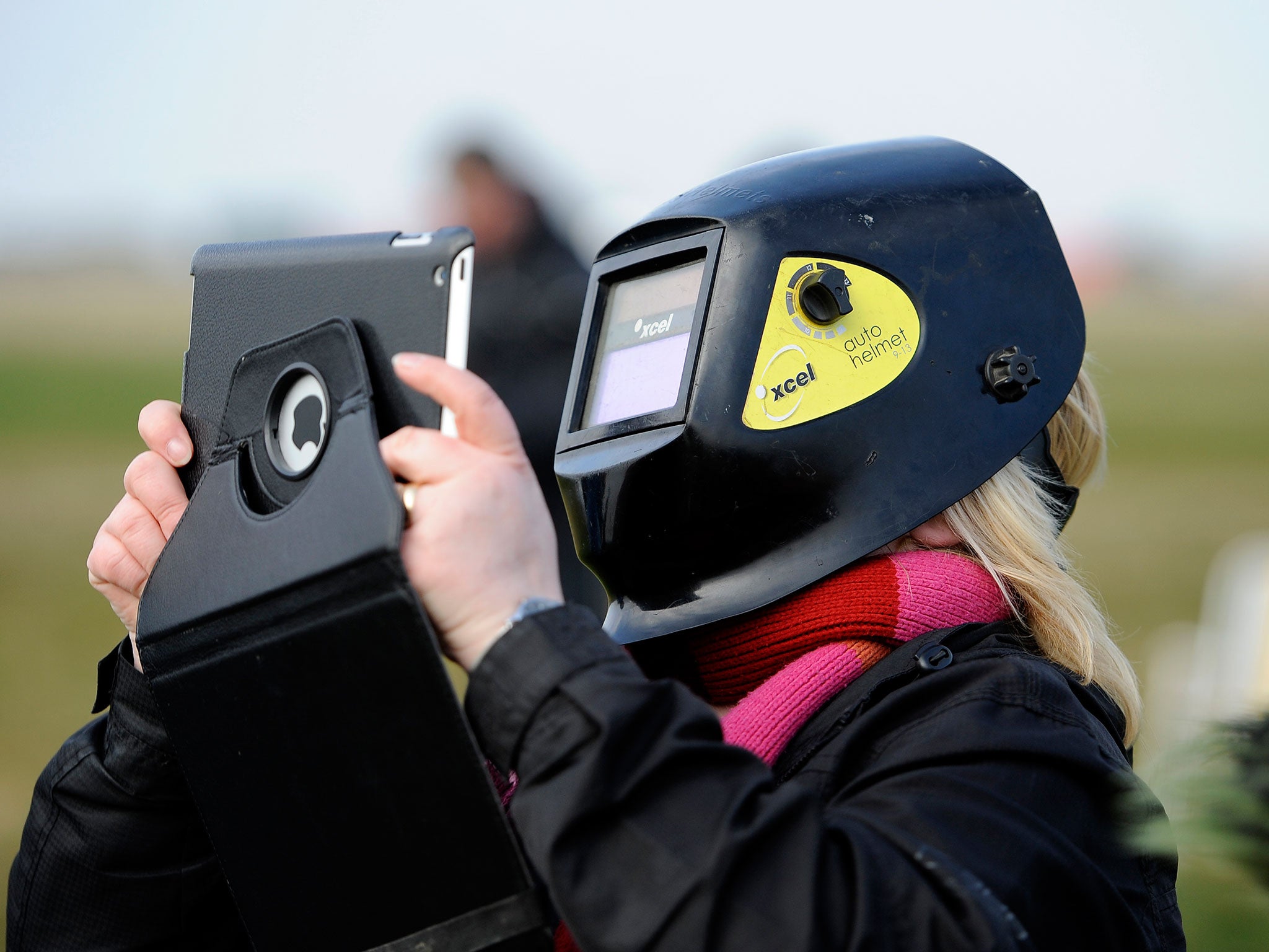 A member of the public takes a picture on her iPad as she wears a welding mask to watch a partial eclipse of the sun, at Stonehenge in Wiltshire