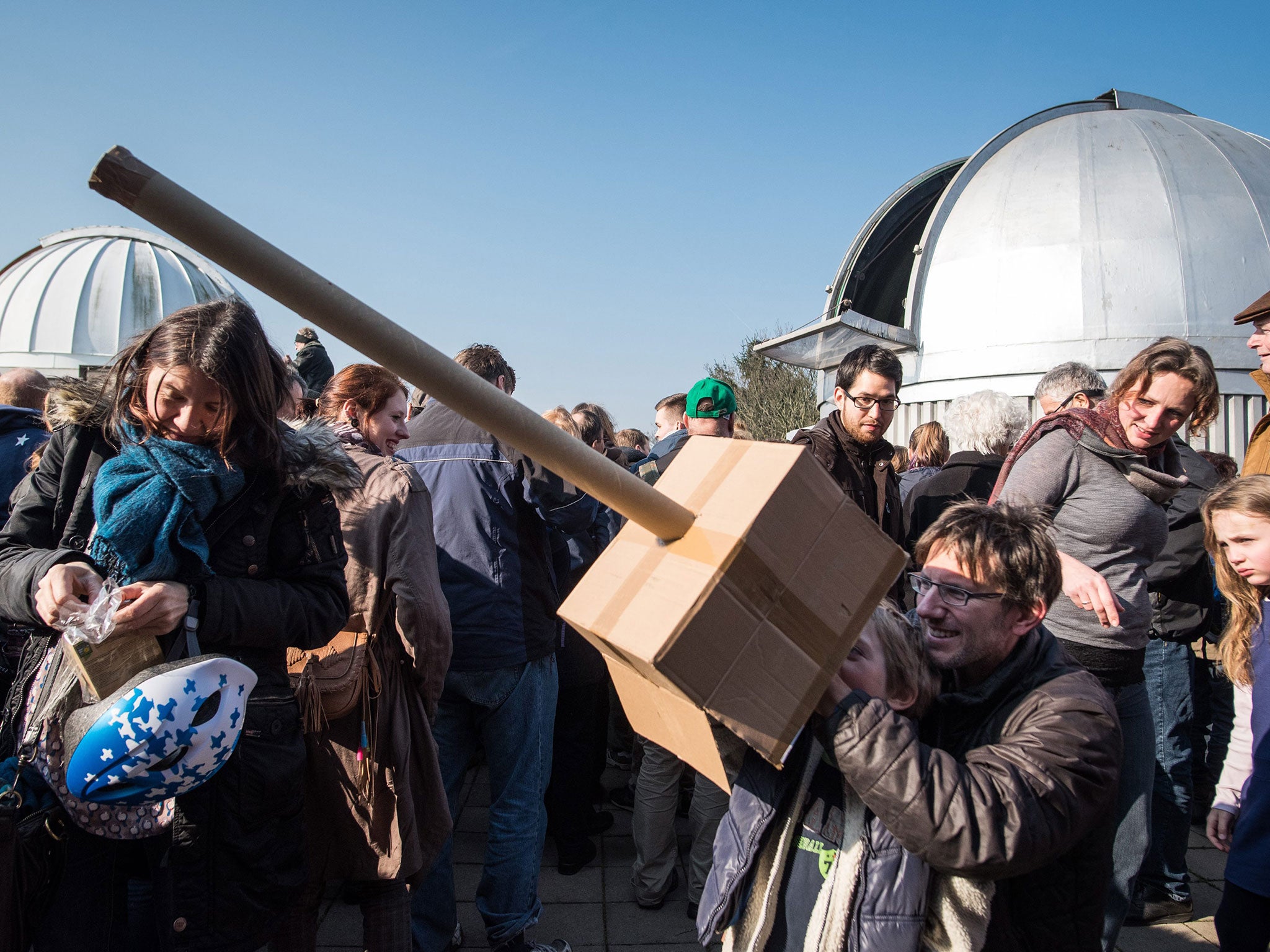 Hobby astronomer Hans-Ulrich and his sun Tillmann gaze at the partial solar eclipse using a self-made pinhole camera made of cardboard in front the observatory in Hanover, Germany