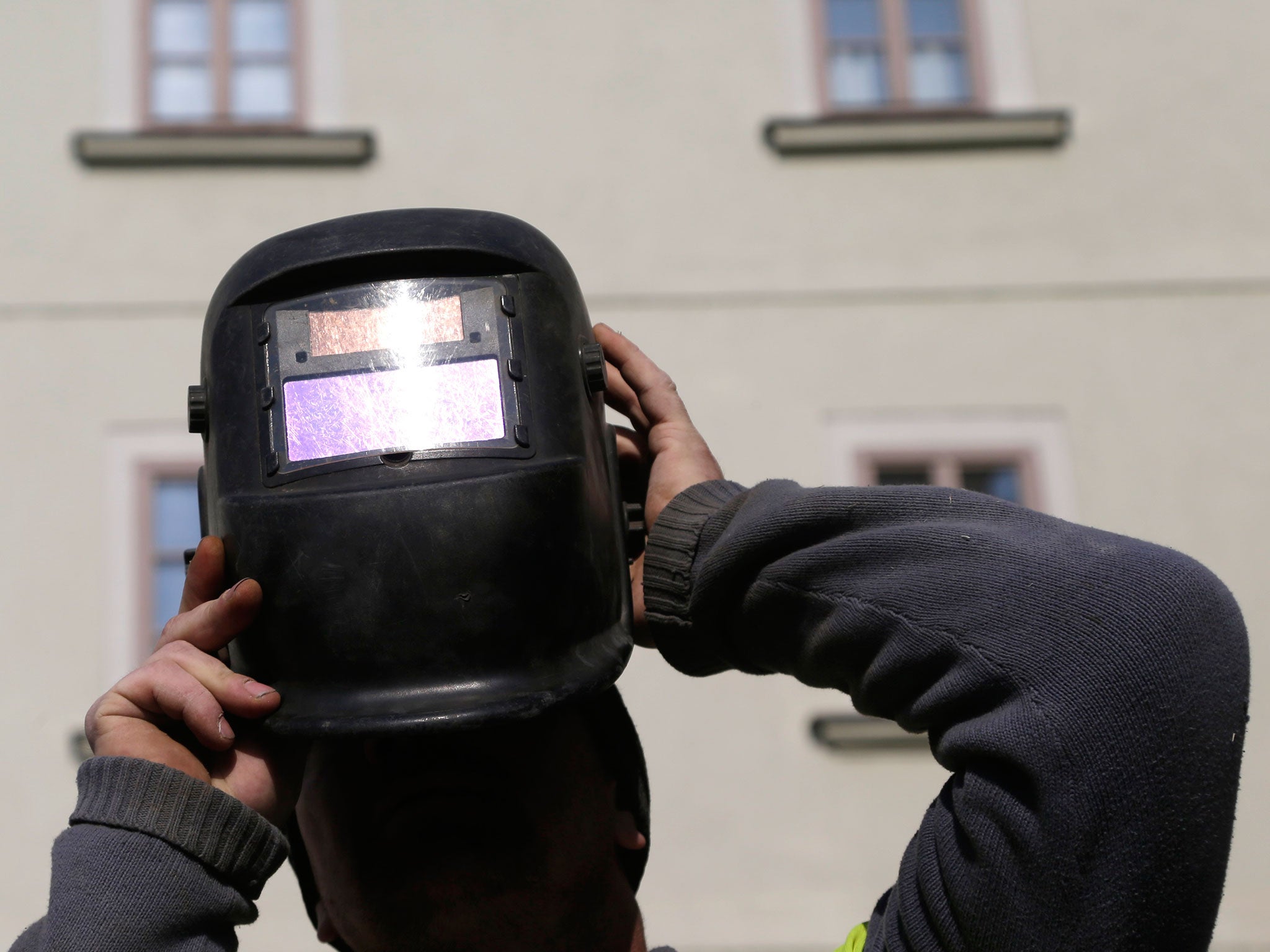 A man looks through welding mask to view the solar eclipse at the Charles Bridge in Prague, Czech Republic