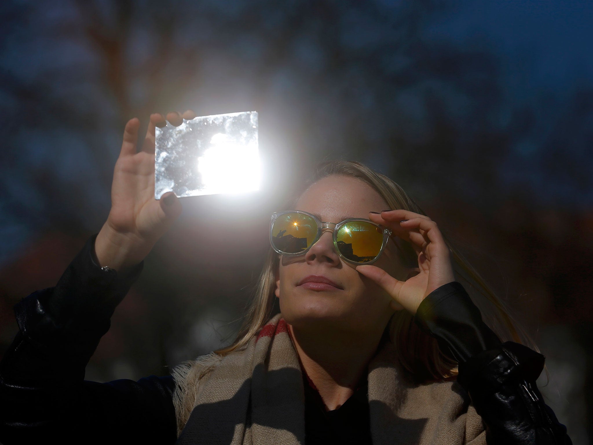 A woman watches a partial solar eclipse in Budapest, Hungary