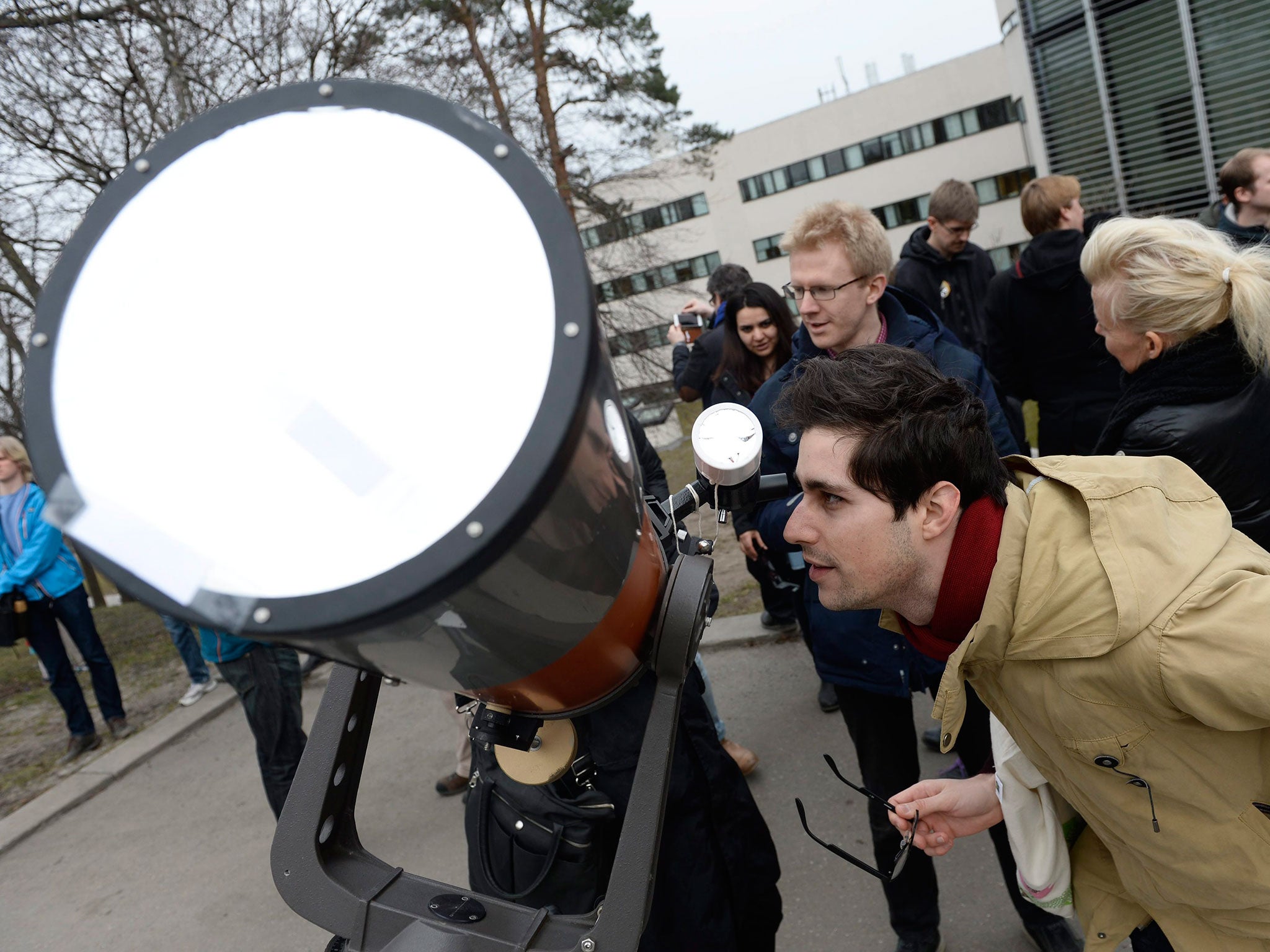 Miko Gruszczynski tries to get a glimpse of the eclipse with a telescope outside the institution for astronmy in Stockholm, Sweden