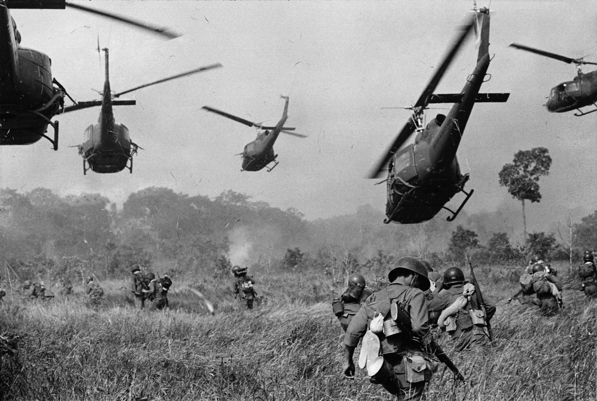 US Army helicopters pour machine gun fire into the treeline to cover the advance of South Vietnamese ground troops in an attack on a Viet Cong camp, Vietnam, March 1965, shot by Horst Faas for AP