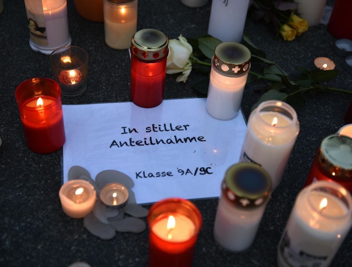 Candles sit on a paper reading "in silent memory, class 9a/9c" in front of the Joseph-Koenig Gymnasium