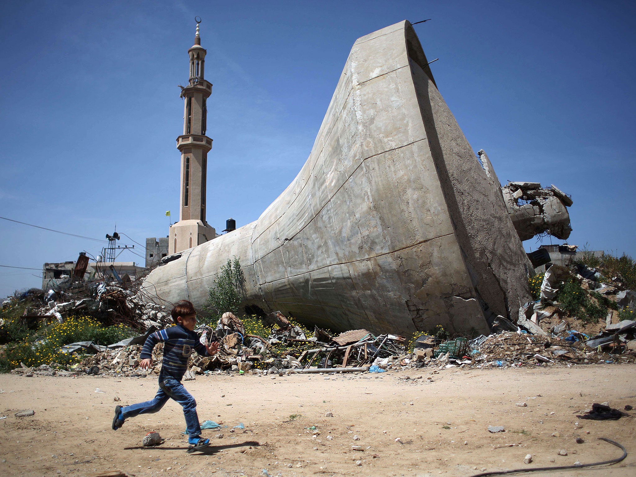 A Palestinian child runs past a water tank that was destroyed in Israeli bombing during the 50-day war between Israel and Hamas militants in the summer of 2014, in the village of Khuzaa, east of Khan Yunis, in the southern Gaza Strip