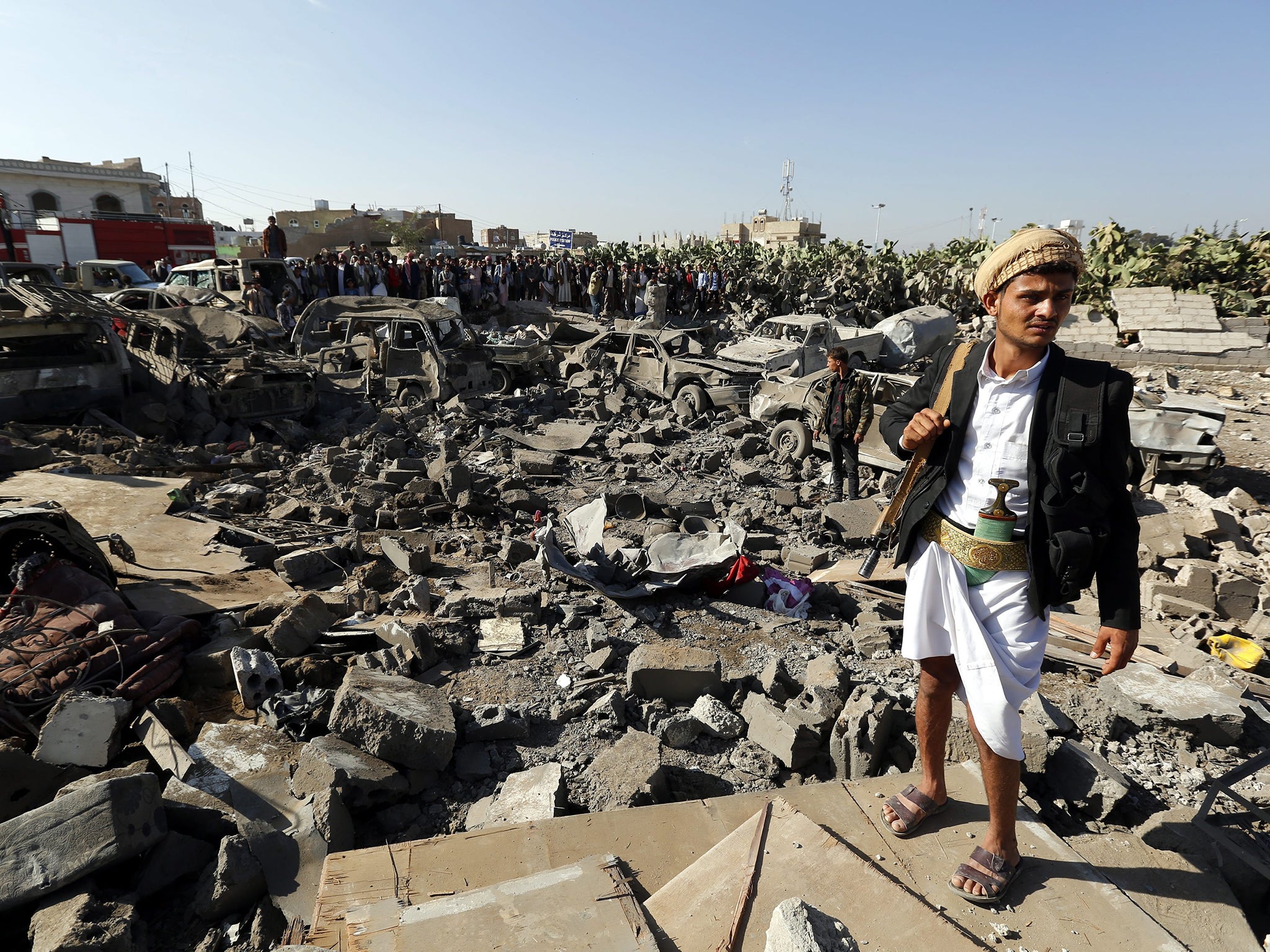 A member of the Houthi militia near vehicles destroyed by a Saudi air strike in Sanaa