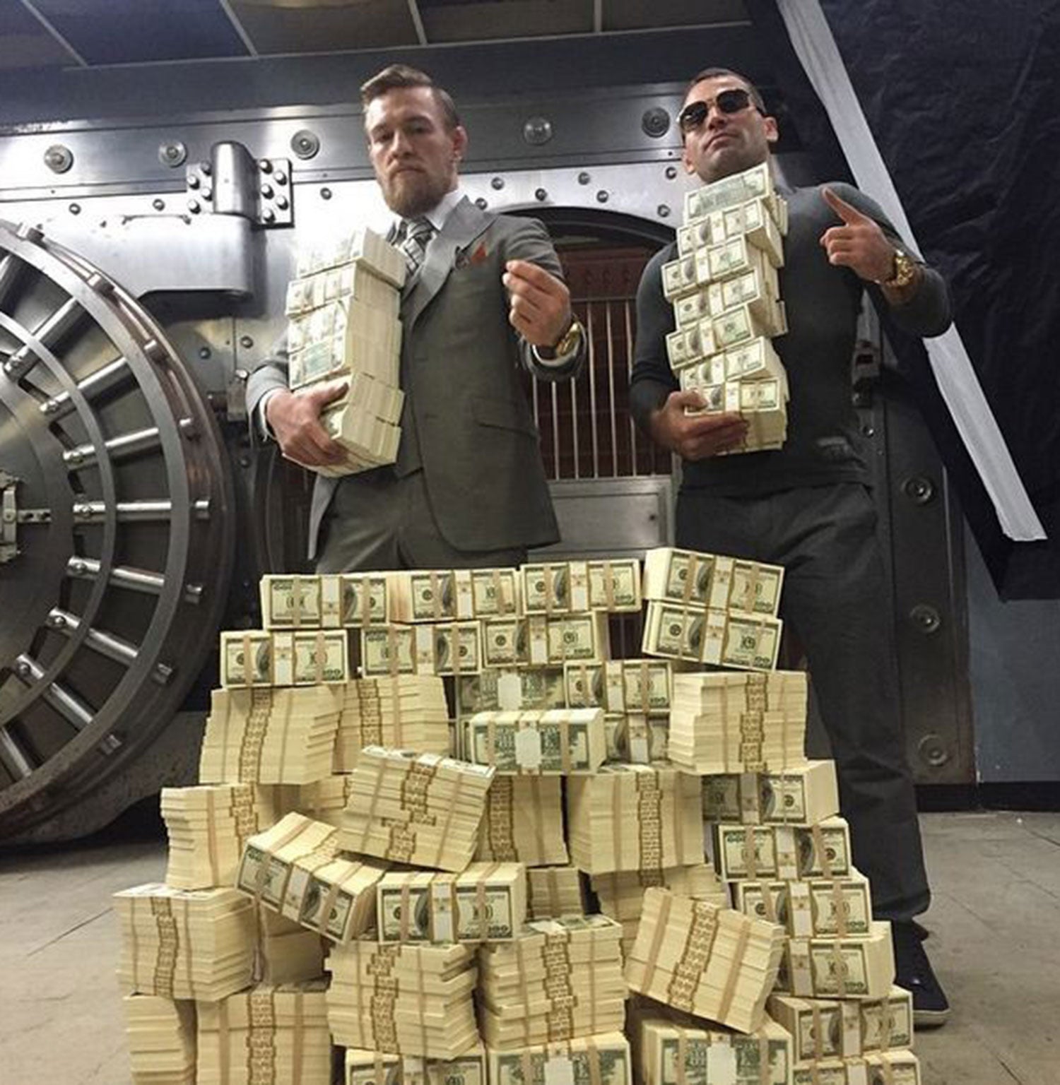 Conor McGregor (L) and his training partner Artem Lobov (R) pose with a stack of dollars