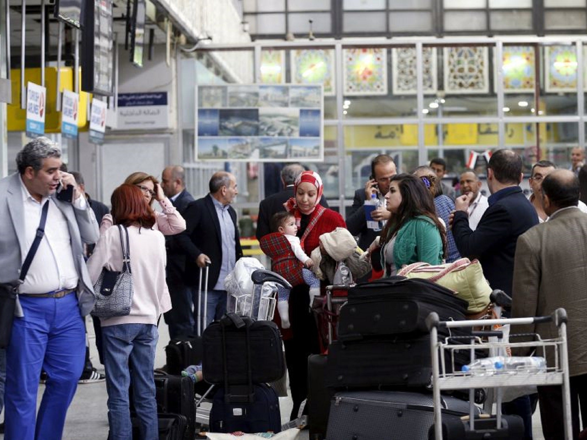 People wait to check in for their flights at Sanaa Airport in Yemen amid fighting between government-supporting fighters and Houthi rebels