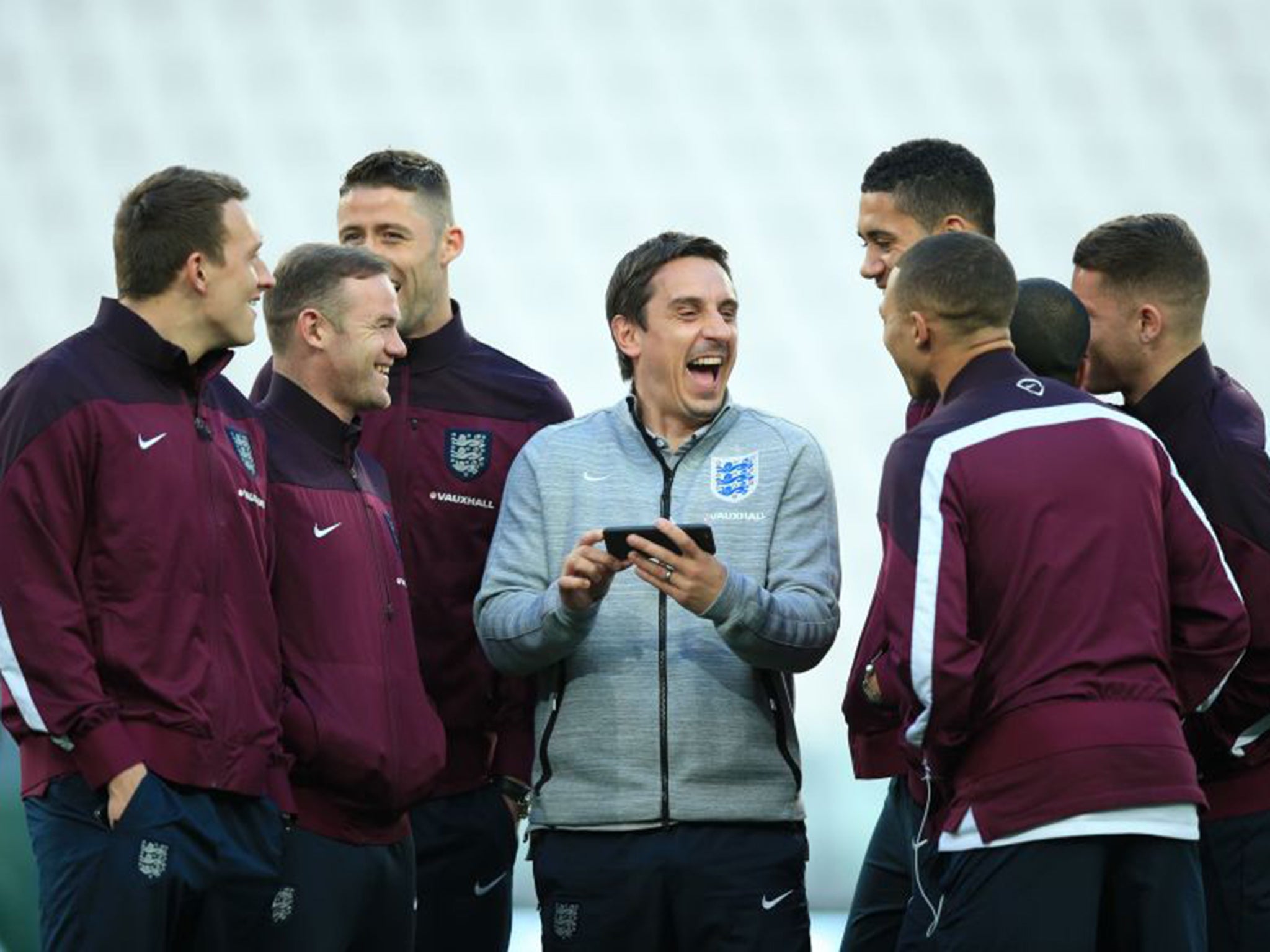 Coach Gary Neville shares a joke with members of the England squad during a visit to Juventus Arena on Monday night