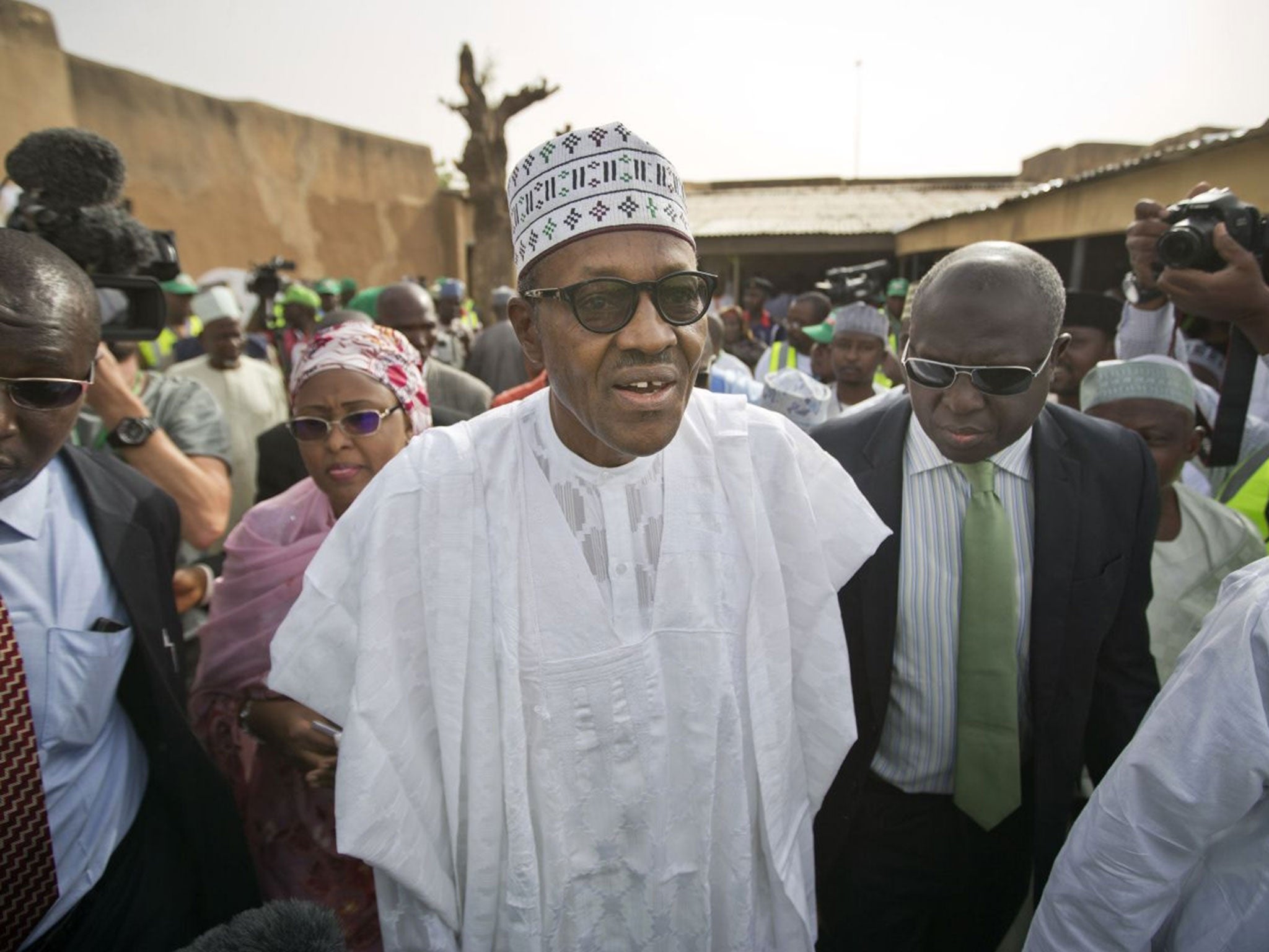 Opposition candidate Gen. Muhammadu Buhari, center, arrives to validate his voting card using a fingerprint reader, prior to casting his vote later in the day, in his home town of Daura, Nigeria Saturday, March 28, 2015. Nigerians went to the polls Saturd