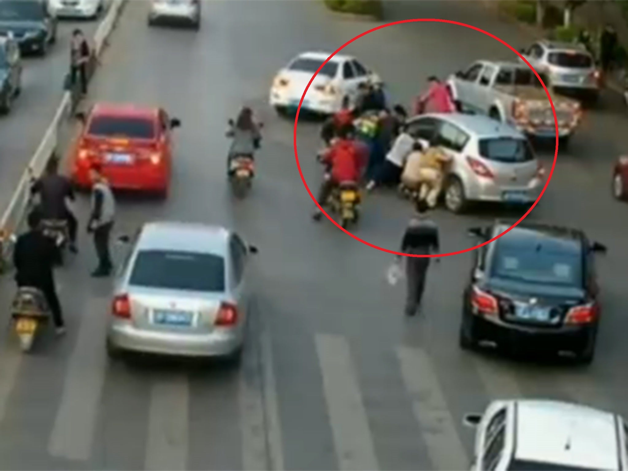 The passersby lift the silver hatchback to rescue the woman