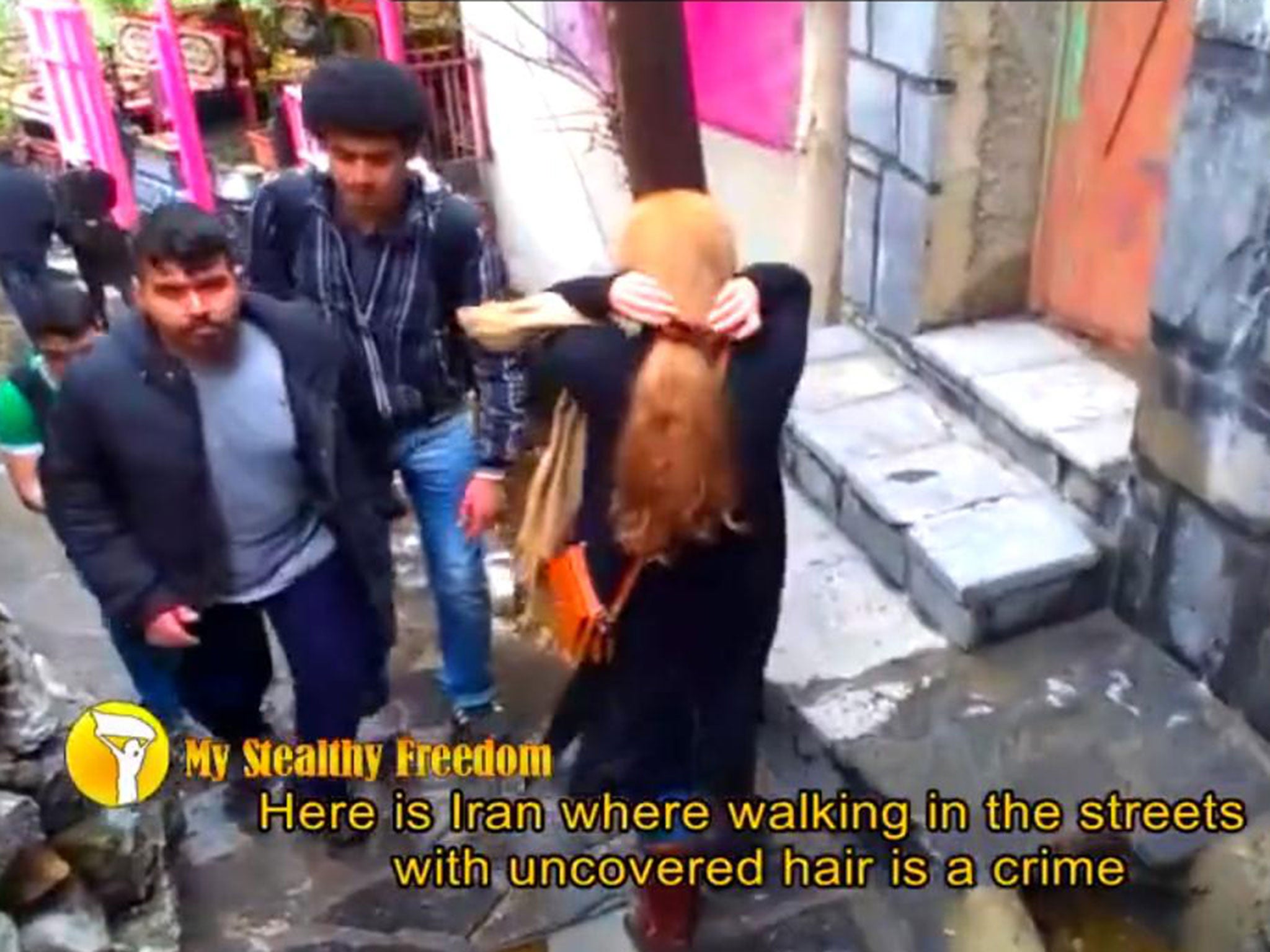 A woman walks through Tehran with her head uncovered