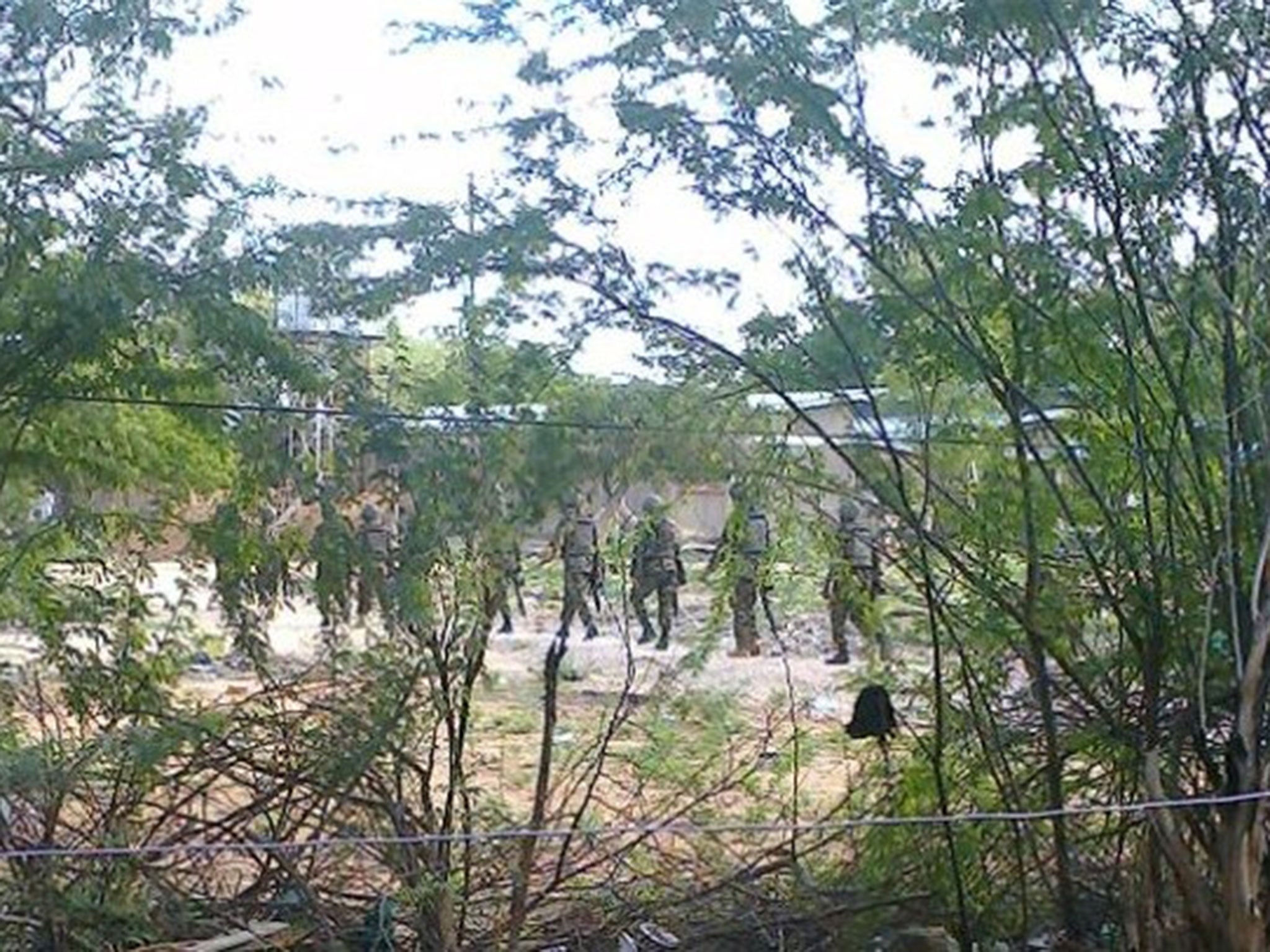 Kenya Defence Forces soldiers move behind a thicket in Garissa town