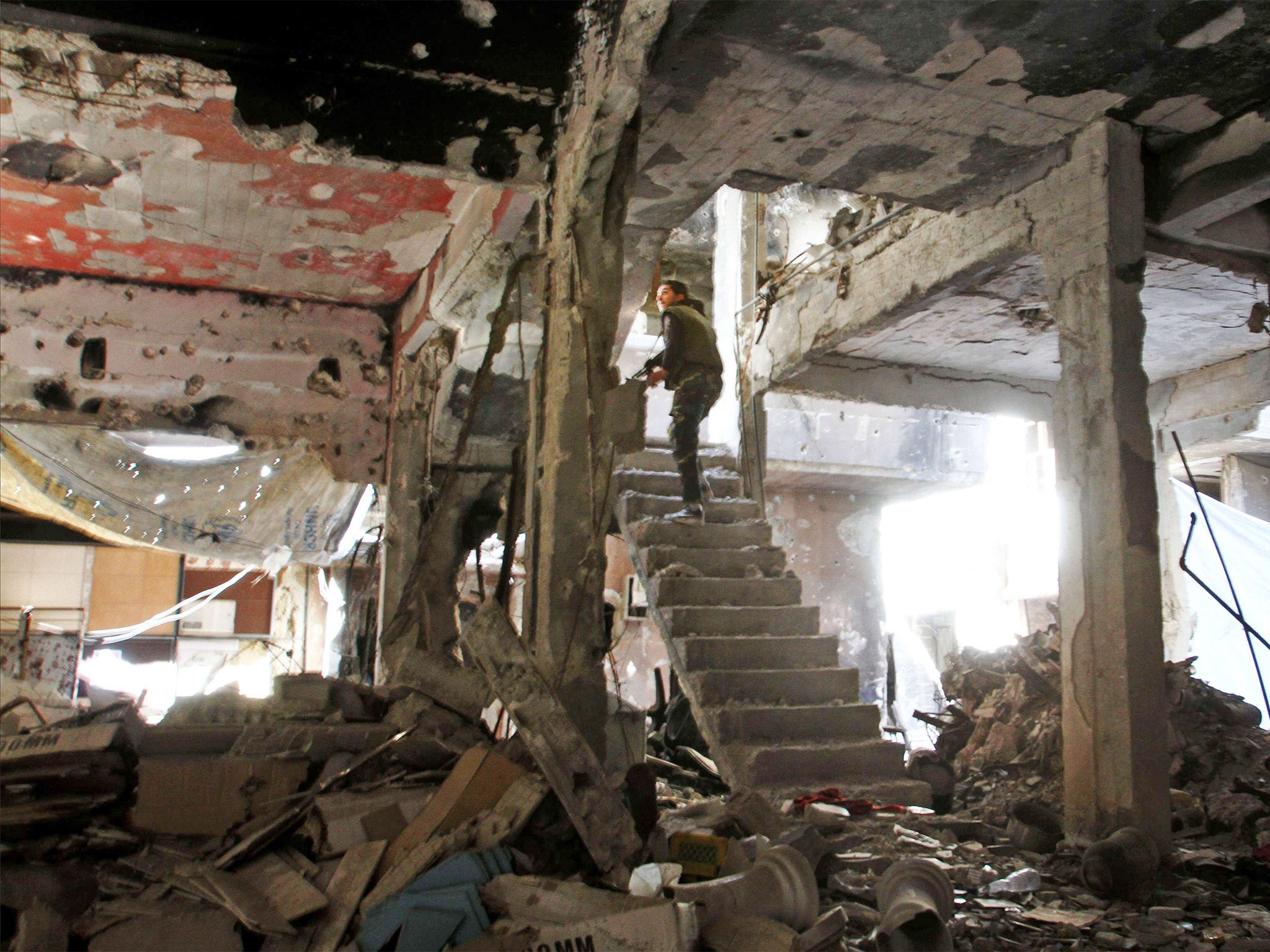 A man stands on a staircase inside a demolished building inside the Yarmouk Palestinian refugee camp