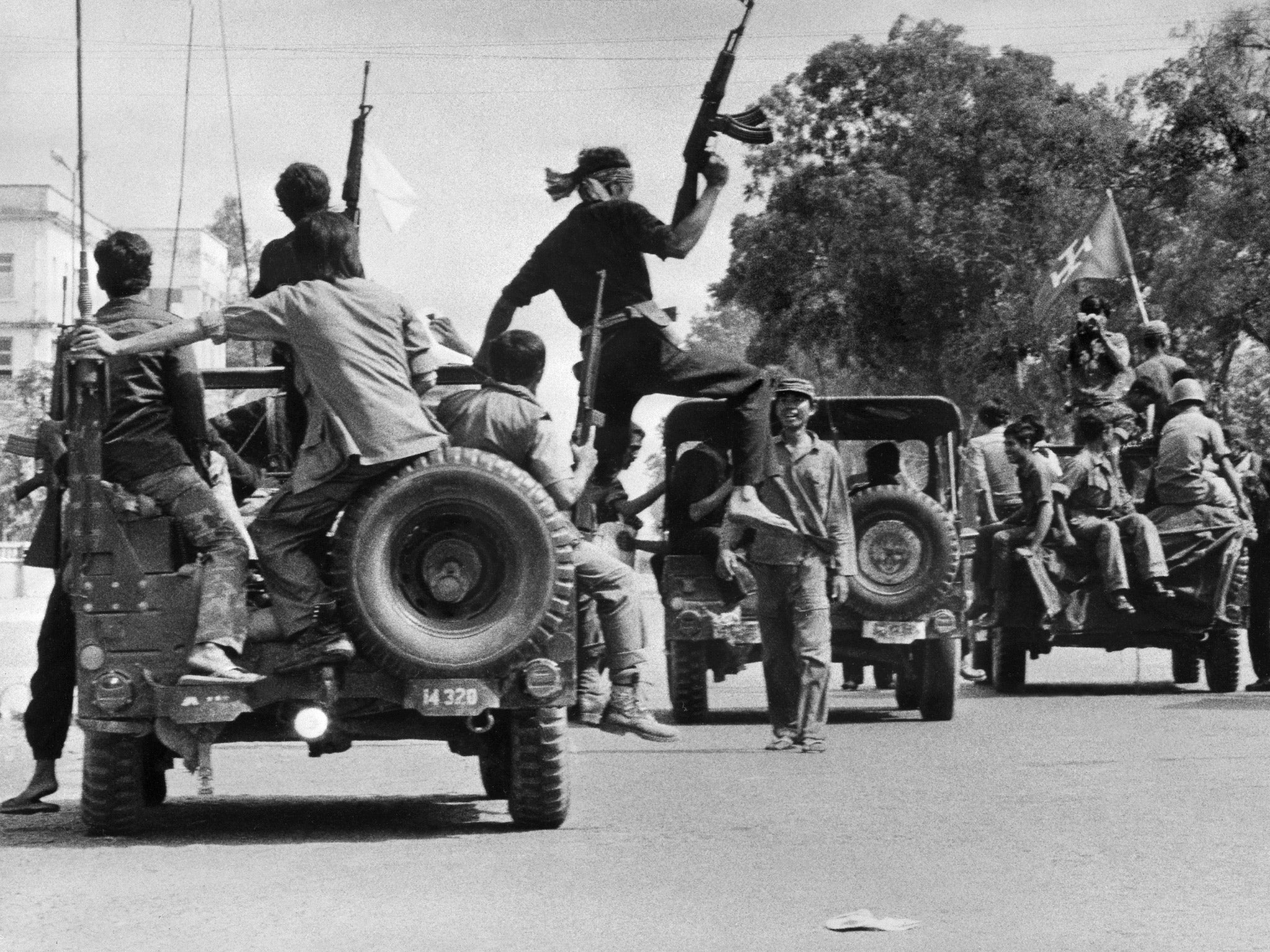 The Khmer Rouge soldiers drive atop jeeps through a street of Phnom Penh, the day Cambodia fell under the control of the Communist Khmer Rouge forces, 17 April 1975 (Getty)