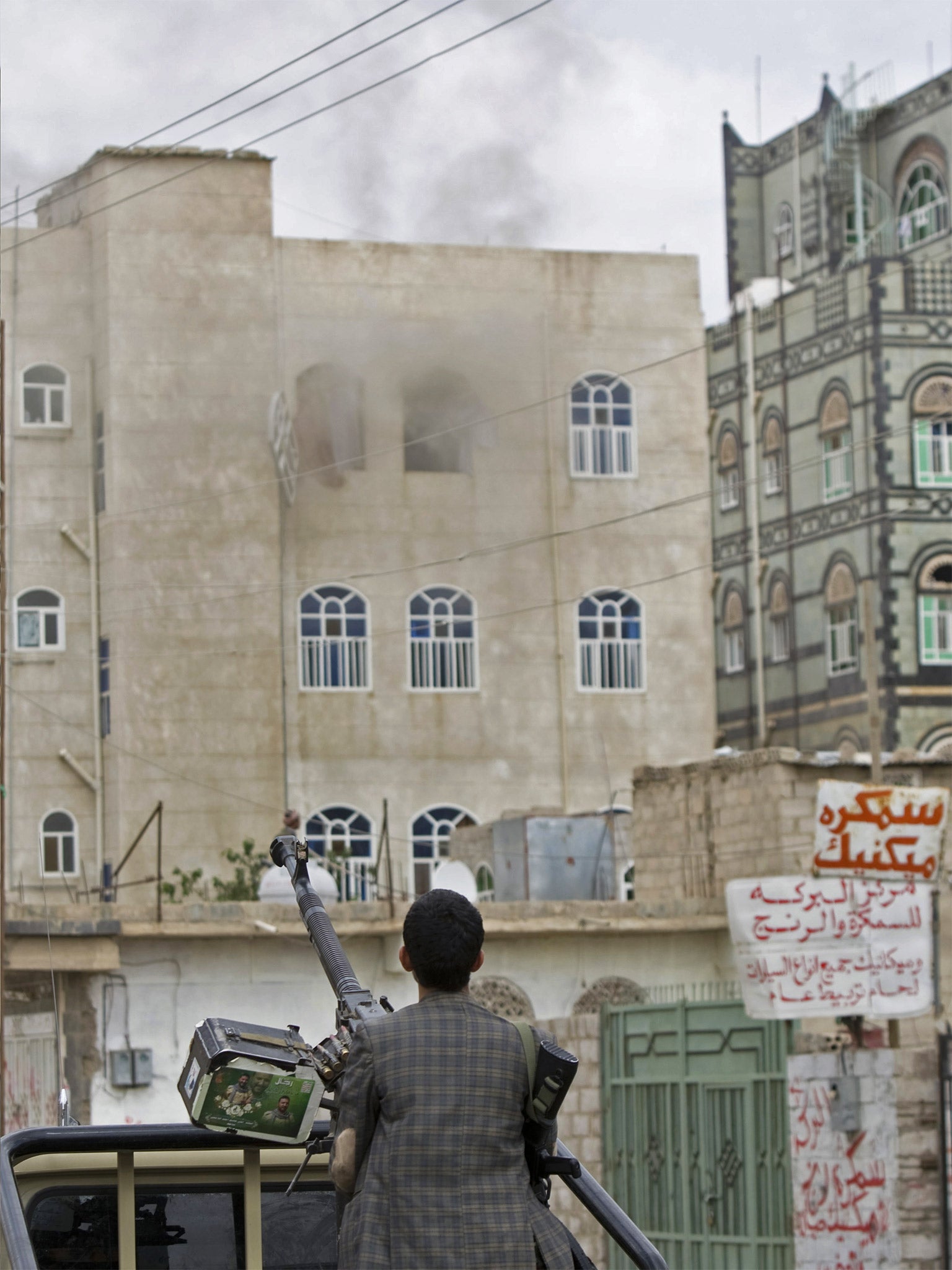 A Houthi fighter looks at smoke rising from a building after a Saudi-led airstrike on a street in Sanaa on Wednesday