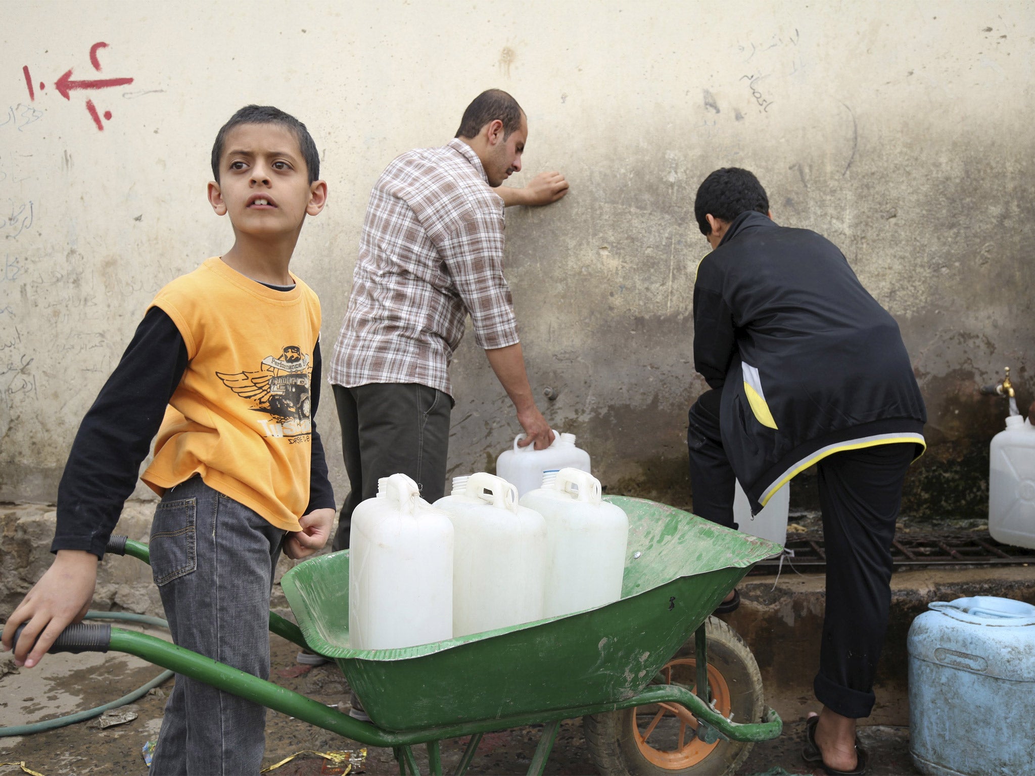 A boy transports containers at a private well as people store water, amid a serious shortage in the Yemeni capital Sanaa