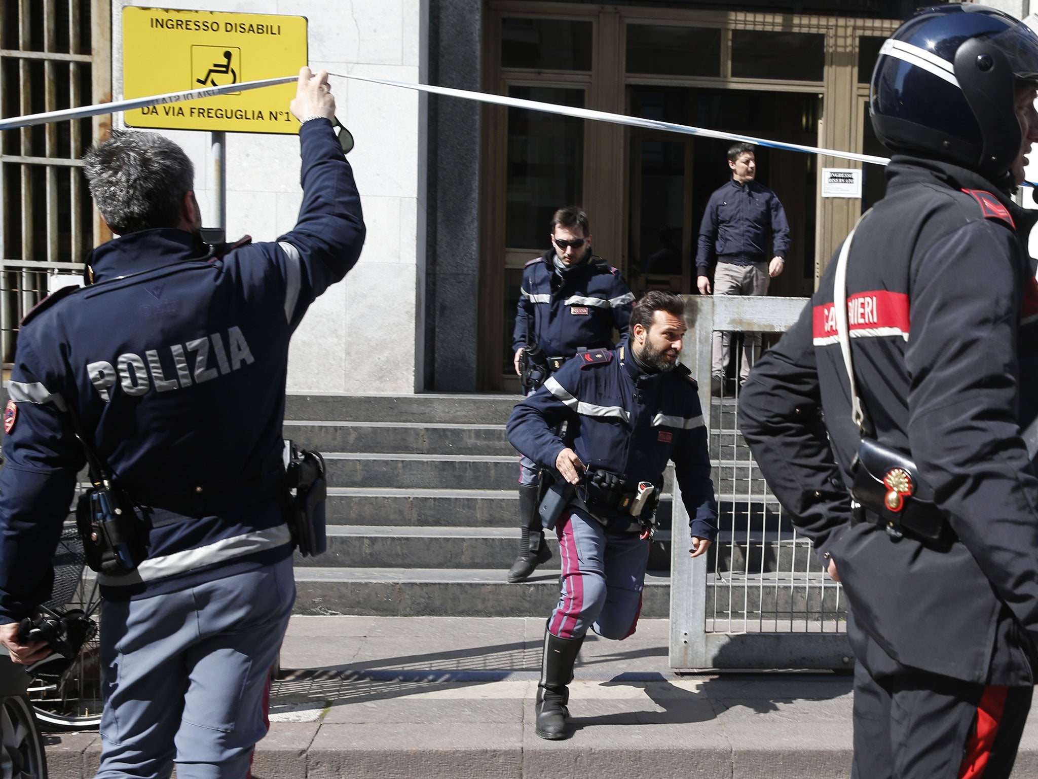 Policemen run out of the tribunal building in Milan, Italy, after a shooting was reported inside a courtroom