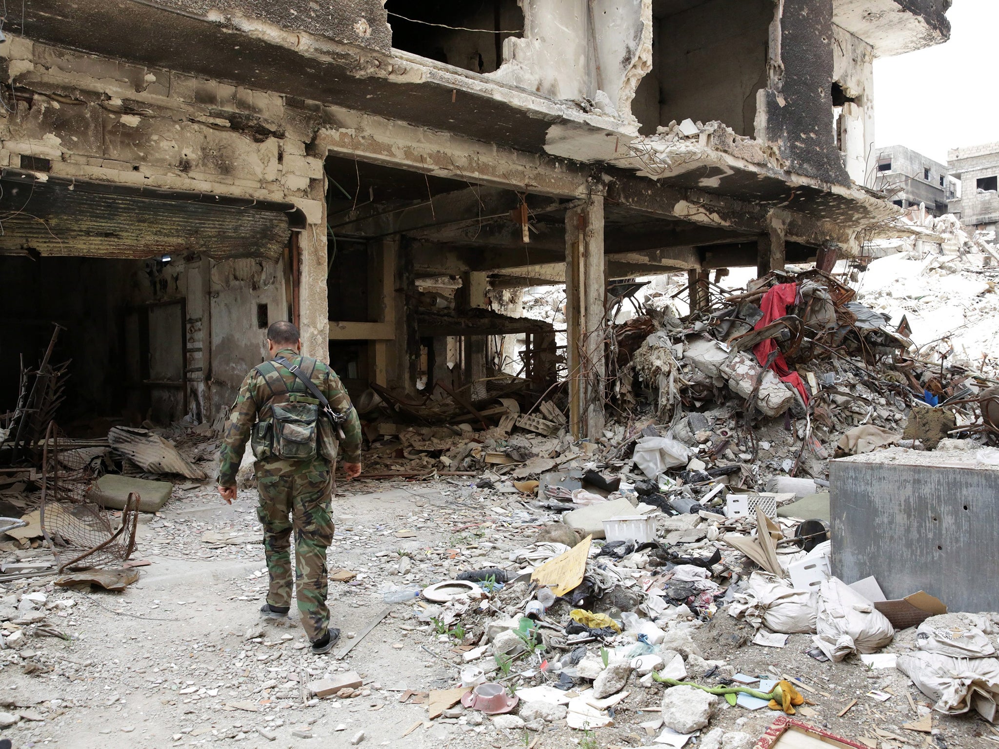 A Palestinian fighter walks through the rubble of the al-Yarmouk Palestinian refugee camp, south of Damascus, Syria