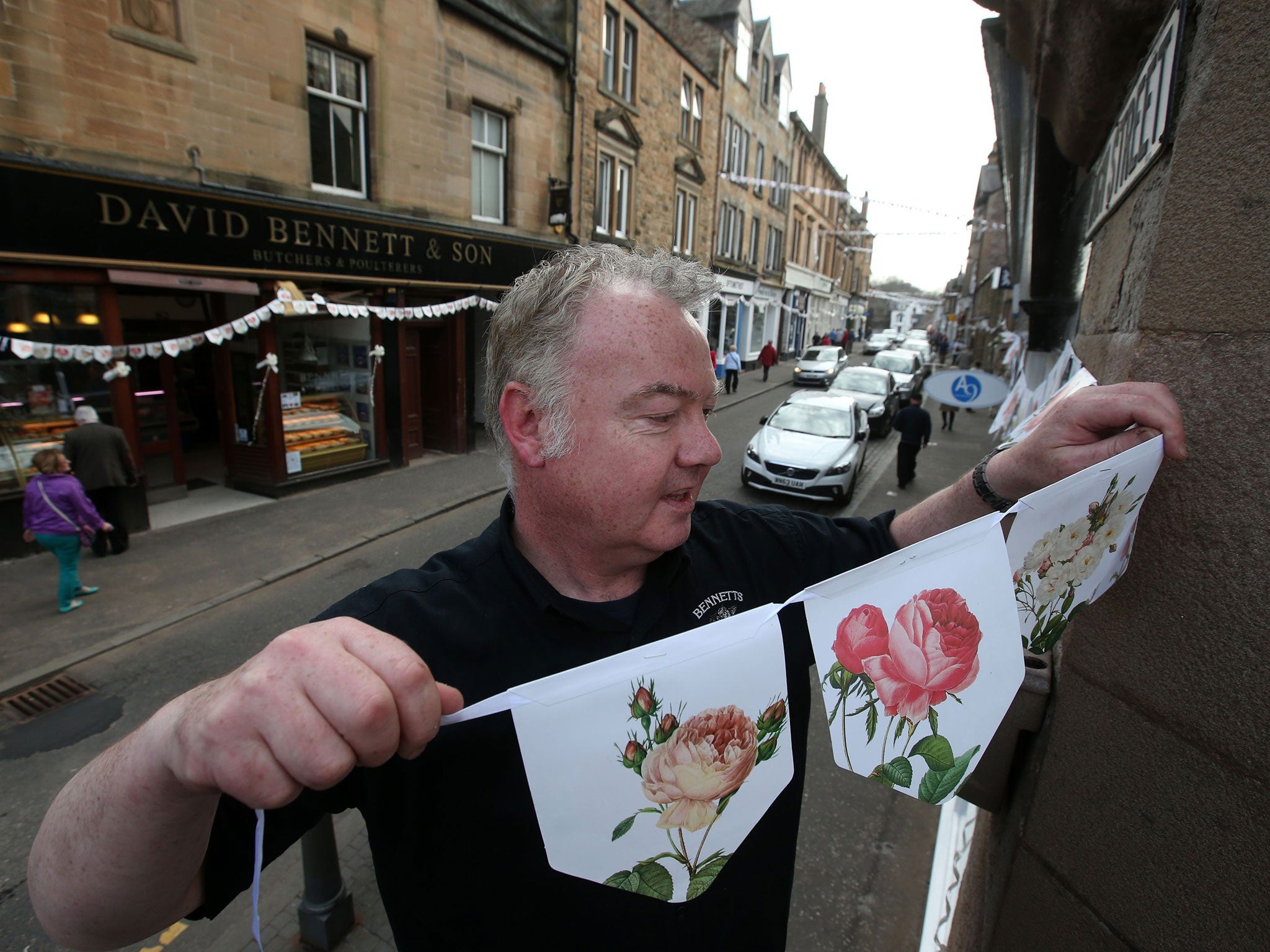 Graham Fleming puts up Bunting in the towns main street, as Local shops in Dunblane High Street decorate their displays in support of local boy Andy Murray ahead of his wedding to Kim Sears