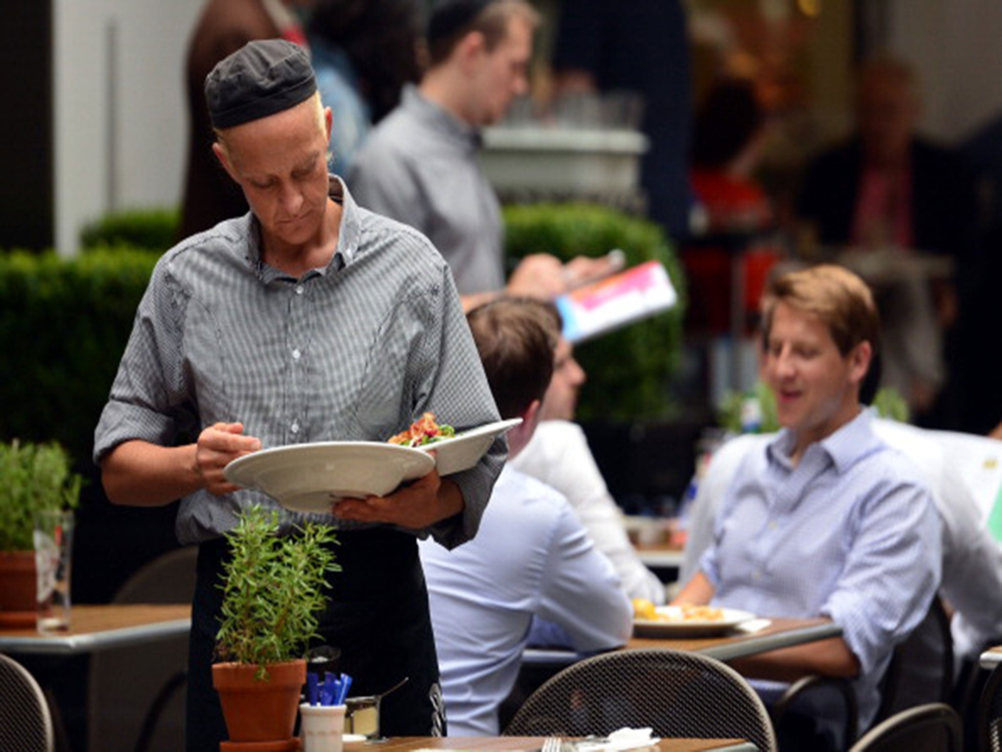 A waitress clears a table at a restaurant in central London