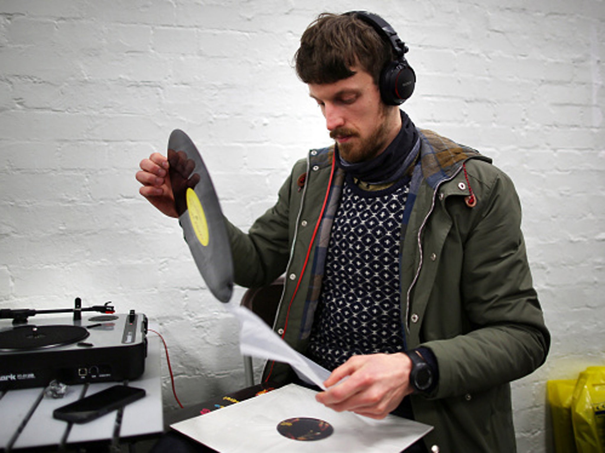 A collector examines an album before playing it on a turntable at the Musicmania Record Fair at Olympia Exhibition Centre in London