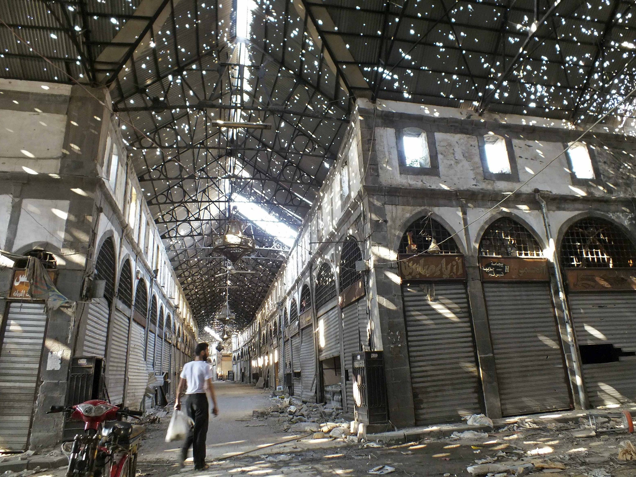 A man walks in the bullet-riddled souk of Homs