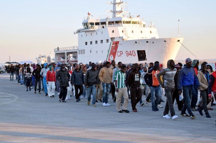 Shipwrecked migrants disembark from a rescue vessel as they arrive in the Italian port of Augusta in Sicily on April 16, 2015.