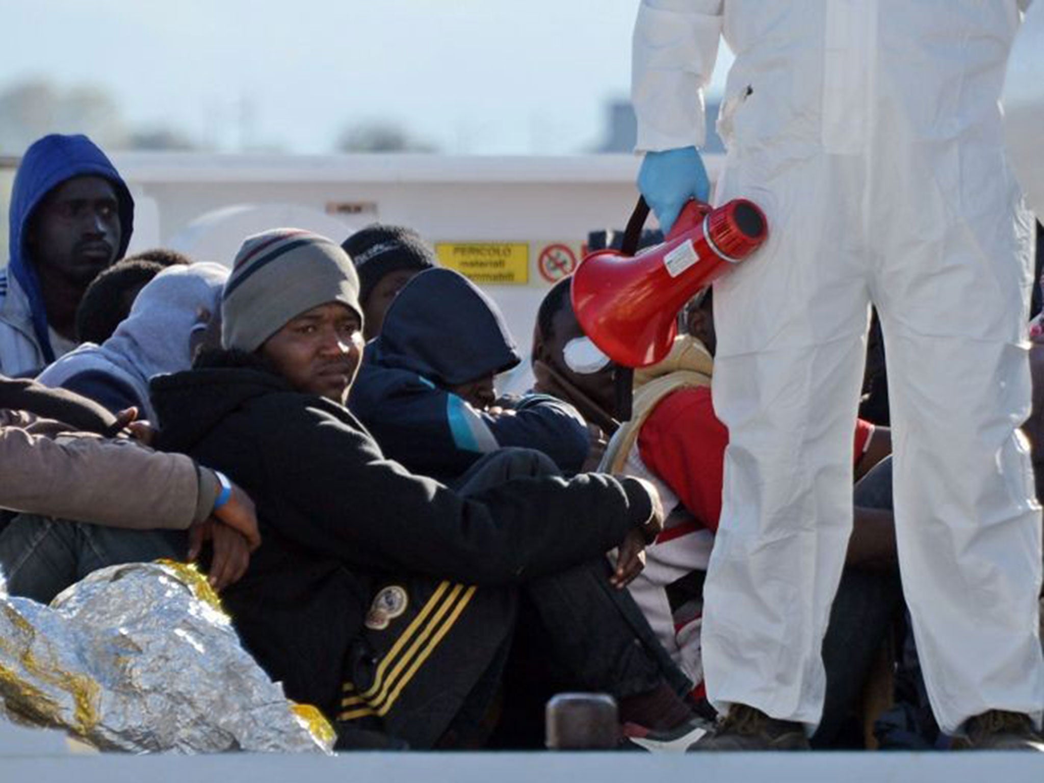 Shipwrecked migrants sit on the deck of a rescue vessel as they arrive in the Italian port of Augusta in Sicily on April 16, 2015.