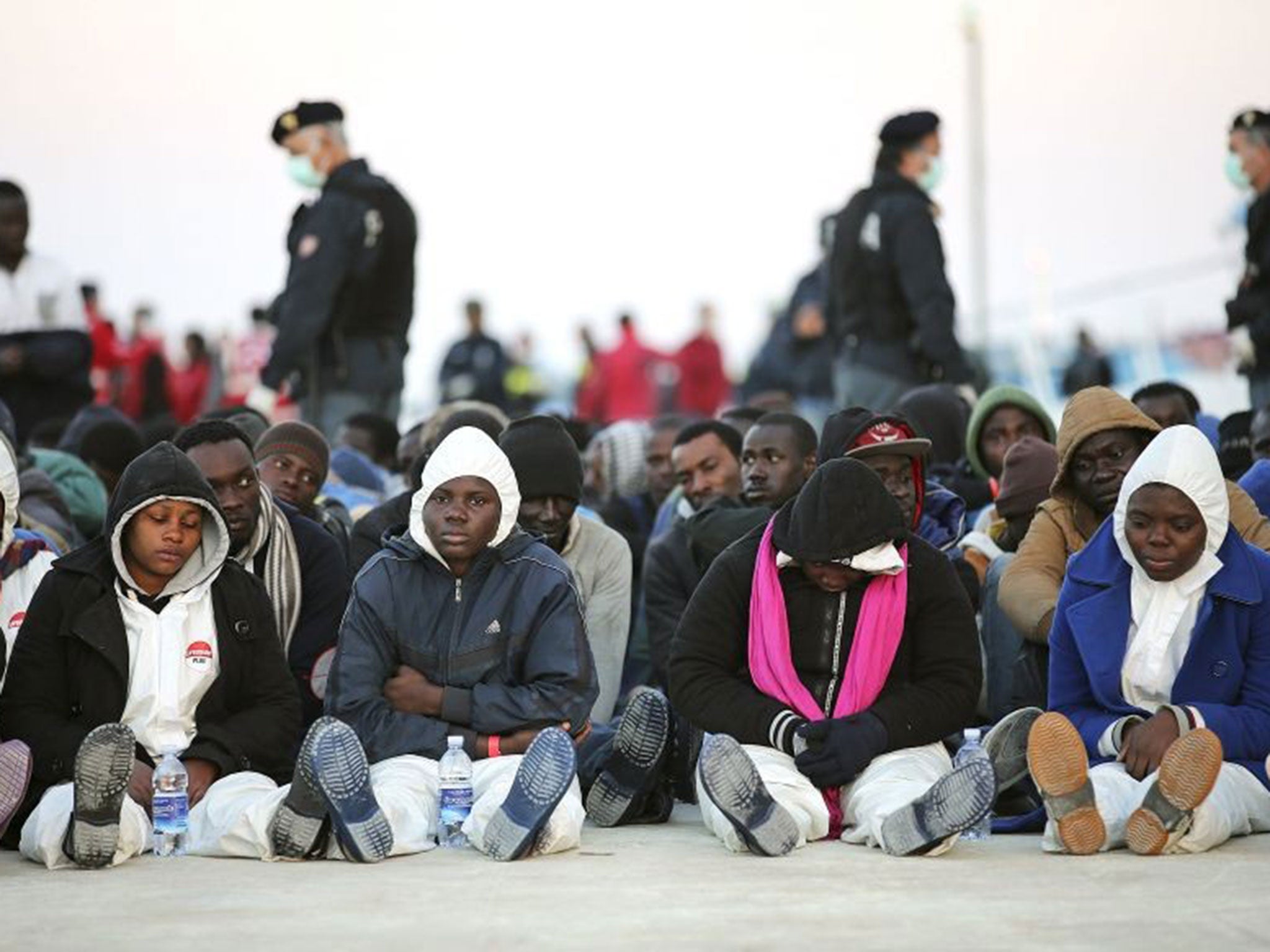 Migrants rest after disembarking in the Sicilian harbour of Augusta on 16 April