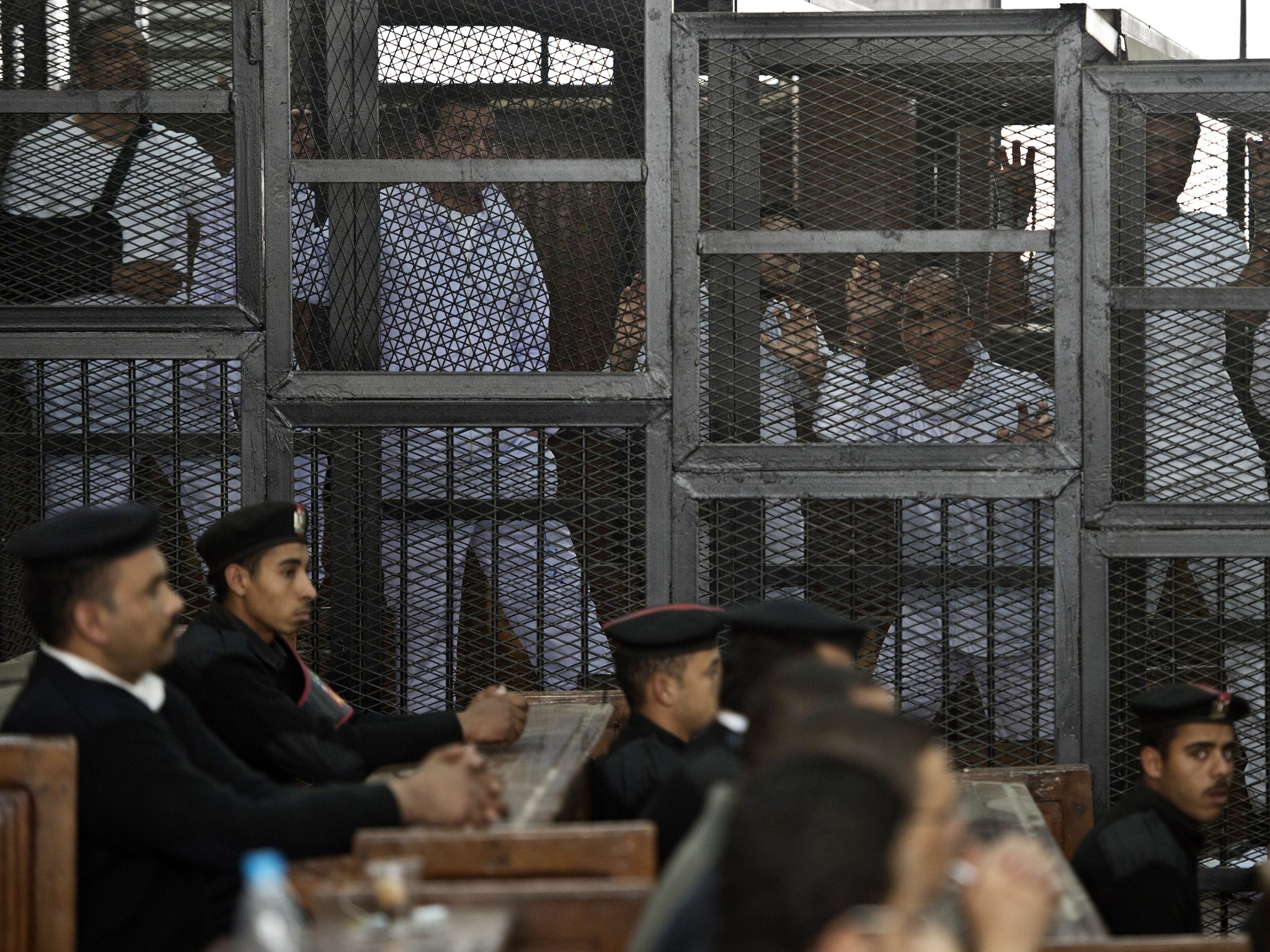 Peter Greste, Mohamed Fahmy and Baher Mohamed stand in the defendants' cage at their trial in Cairo for allegedly support the Muslim Brotherhood