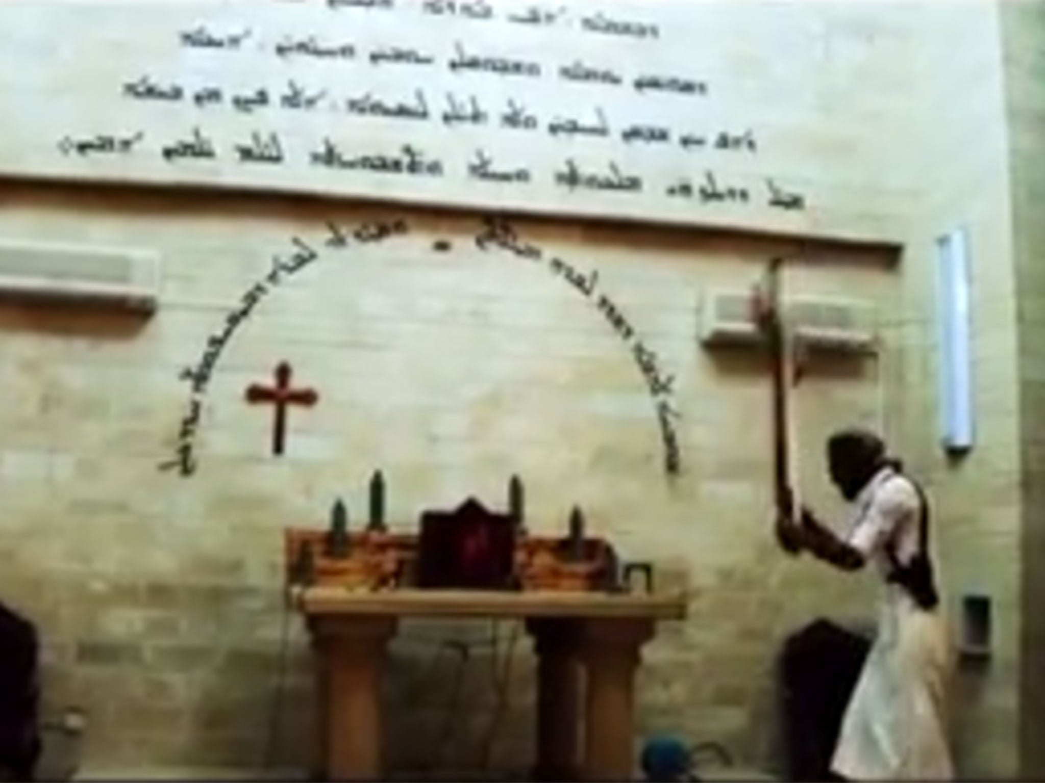 An Isis militant smashes a cross on an altar