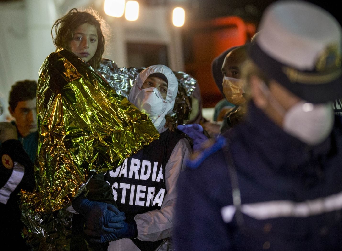 A migrant is helped disembark in the Sicilian harbor of Pozzallo, Italy, early Monday